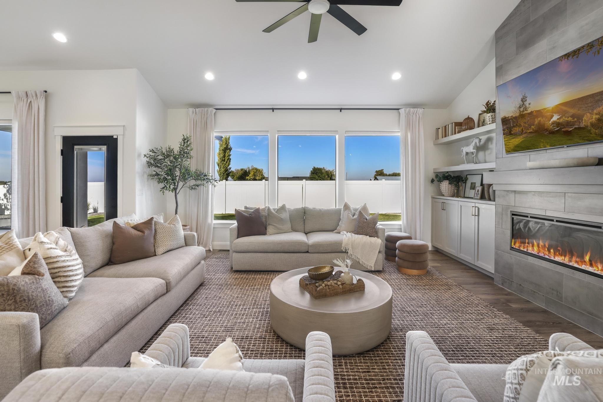 Living room with wood finished floors, a tile fireplace, recessed lighting, and a ceiling fan