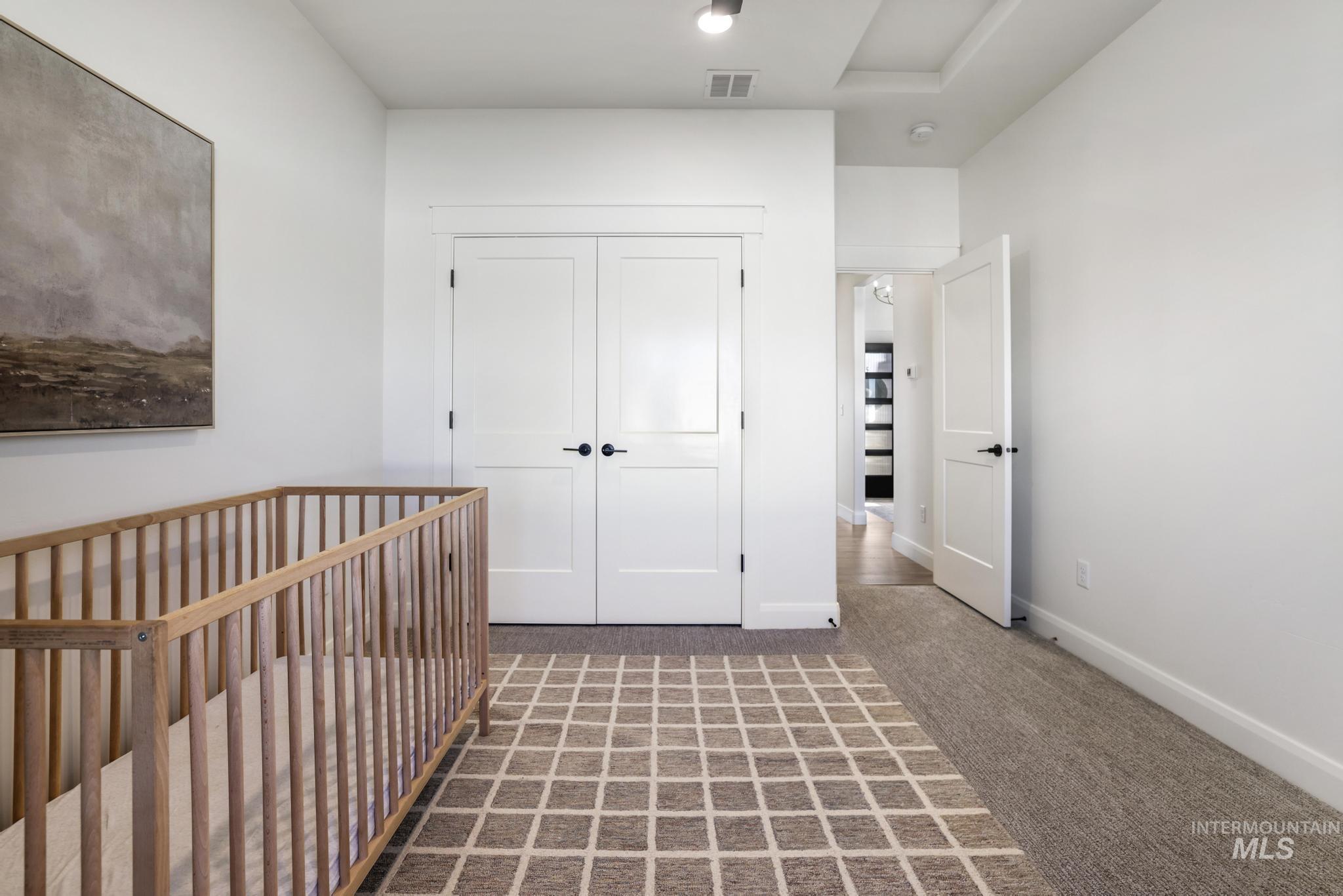 Unfurnished bedroom with carpet floors, a nursery area, and a closet