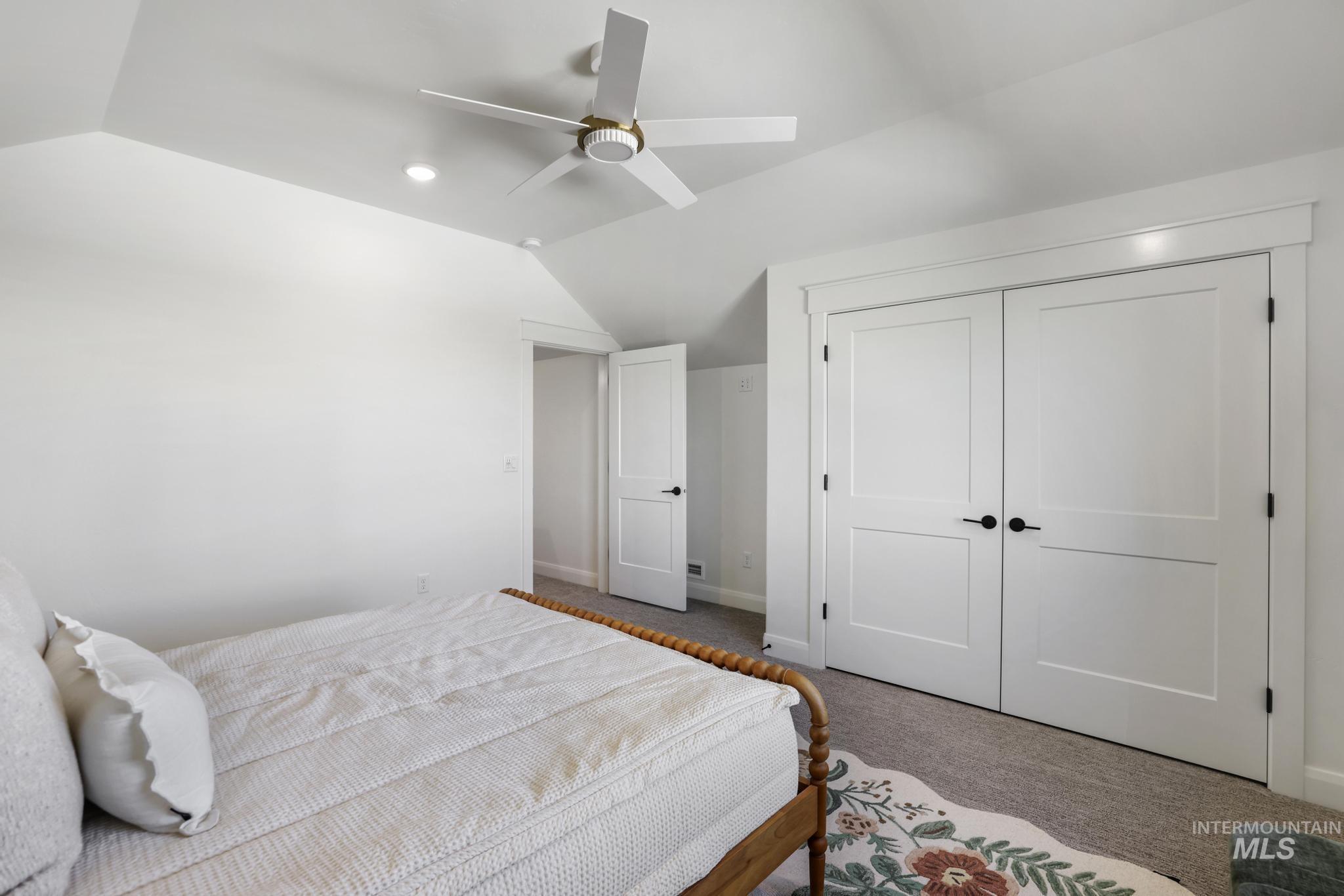 Bedroom featuring vaulted ceiling, carpet floors, a closet, and ceiling fan
