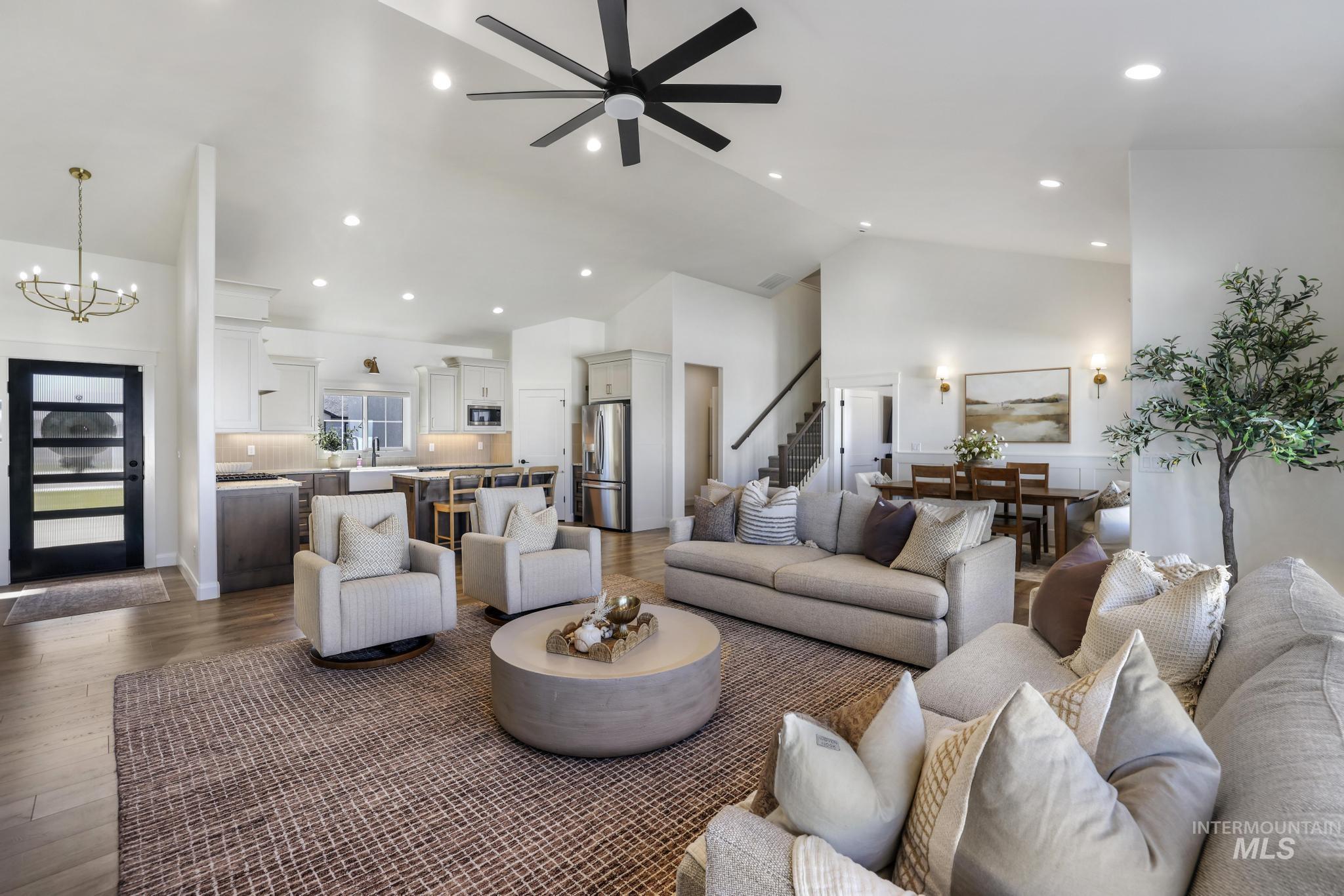 Living room featuring high vaulted ceiling, dark wood-style flooring, recessed lighting, a chandelier, and a ceiling fan