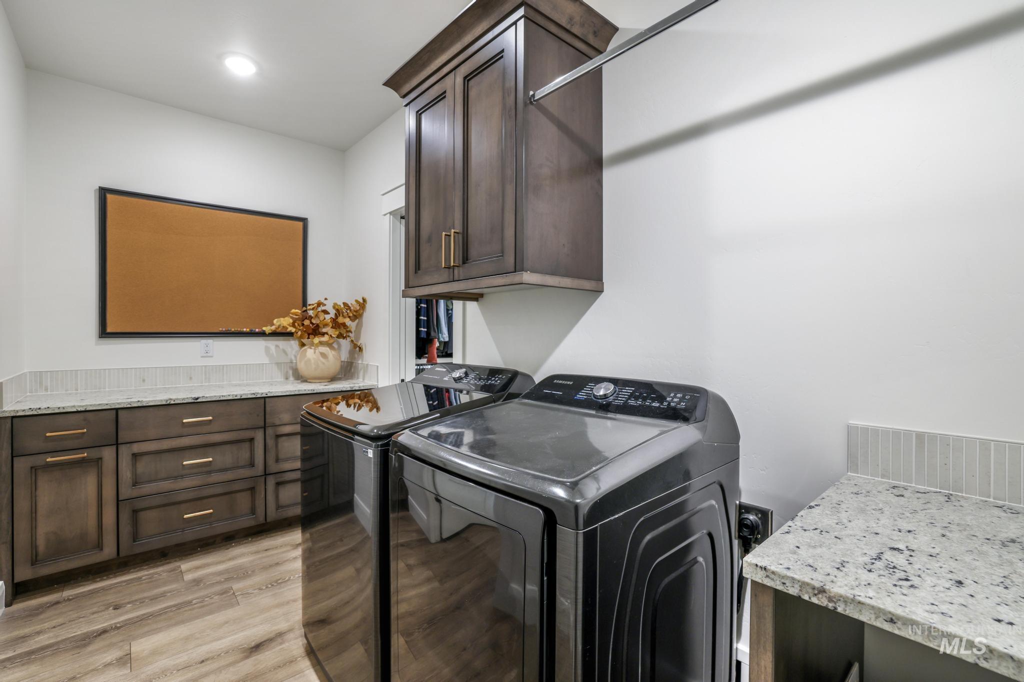 Laundry room with light wood finished floors, cabinet space, and independent washer and dryer