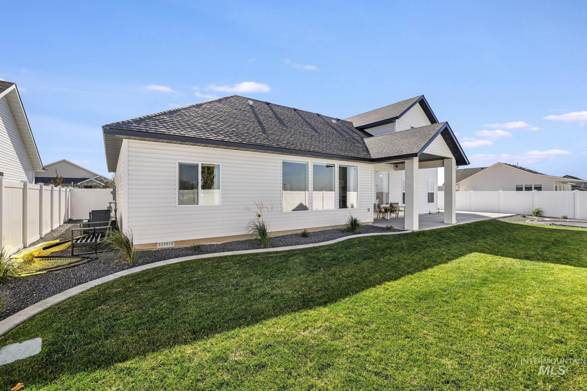 Back of property with a patio, a fenced backyard, and a shingled roof