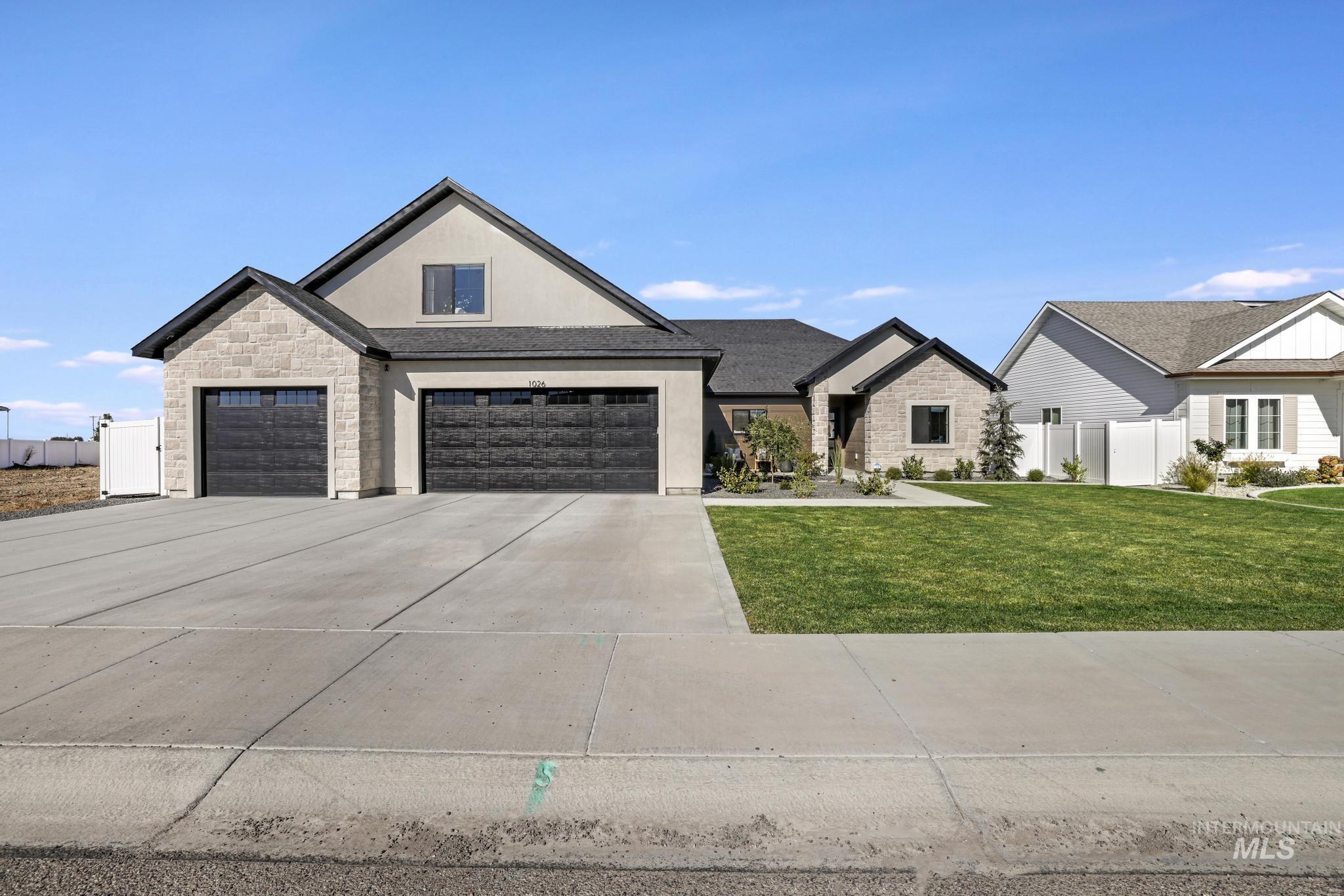 Modern inspired farmhouse with stucco siding, driveway, stone siding, and a garage