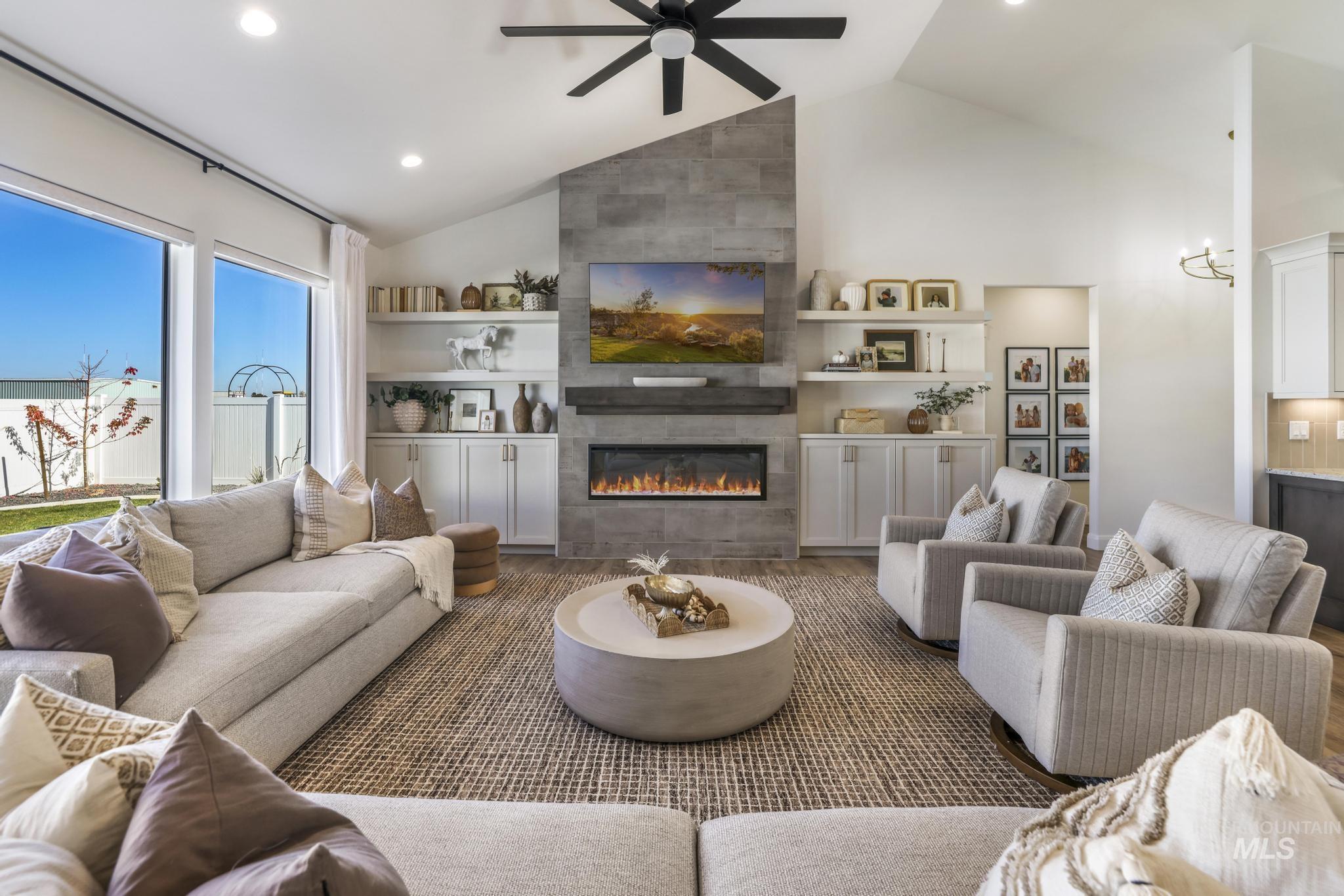 Living area featuring a tiled fireplace, a ceiling fan, high vaulted ceiling, wood finished floors, and recessed lighting