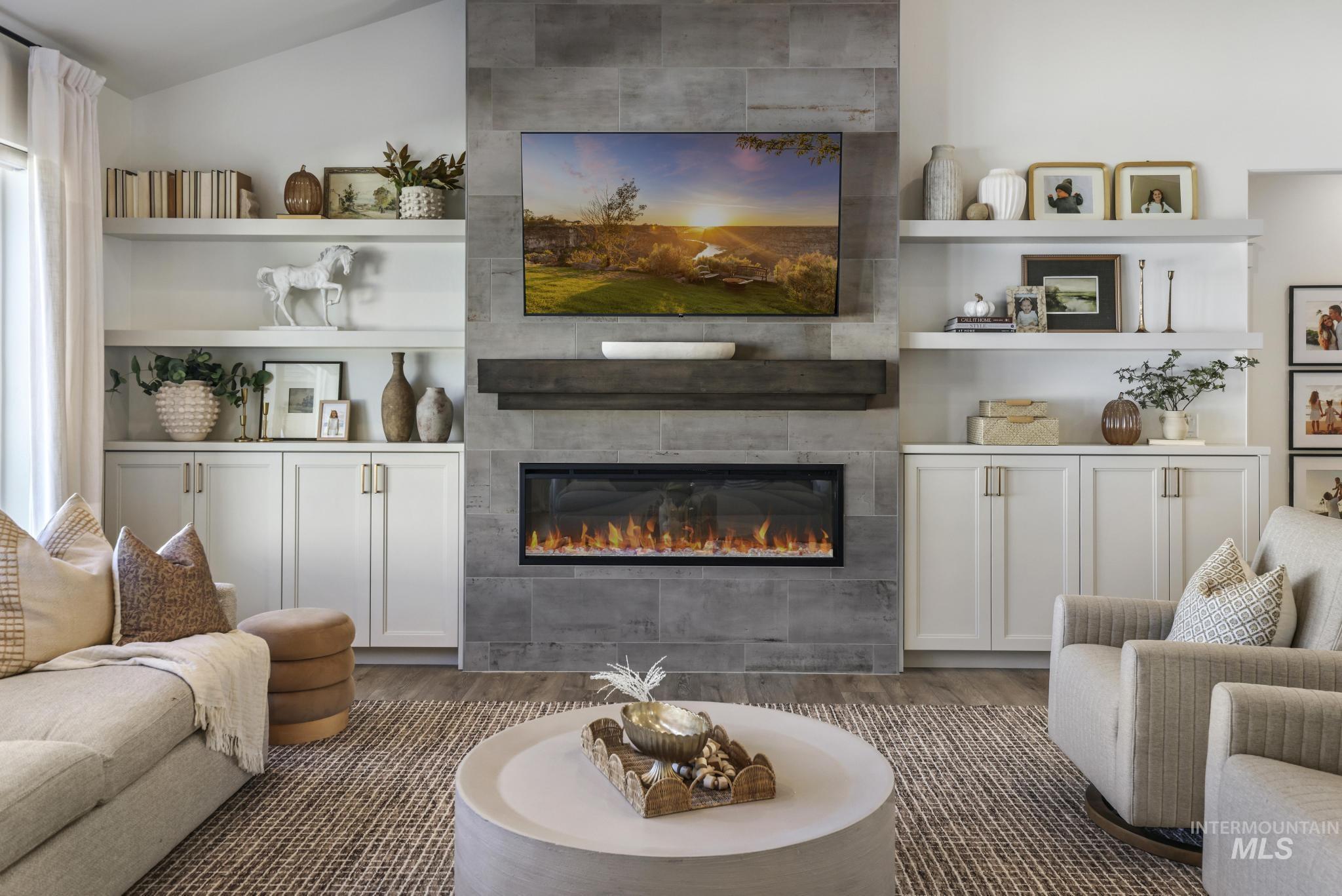 Living room featuring dark wood-style floors, a tile fireplace, and vaulted ceiling
