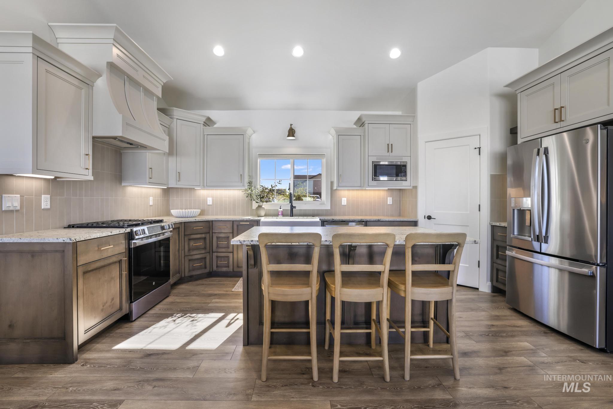 Kitchen with stainless steel appliances, a center island, backsplash, dark wood-type flooring, and recessed lighting
