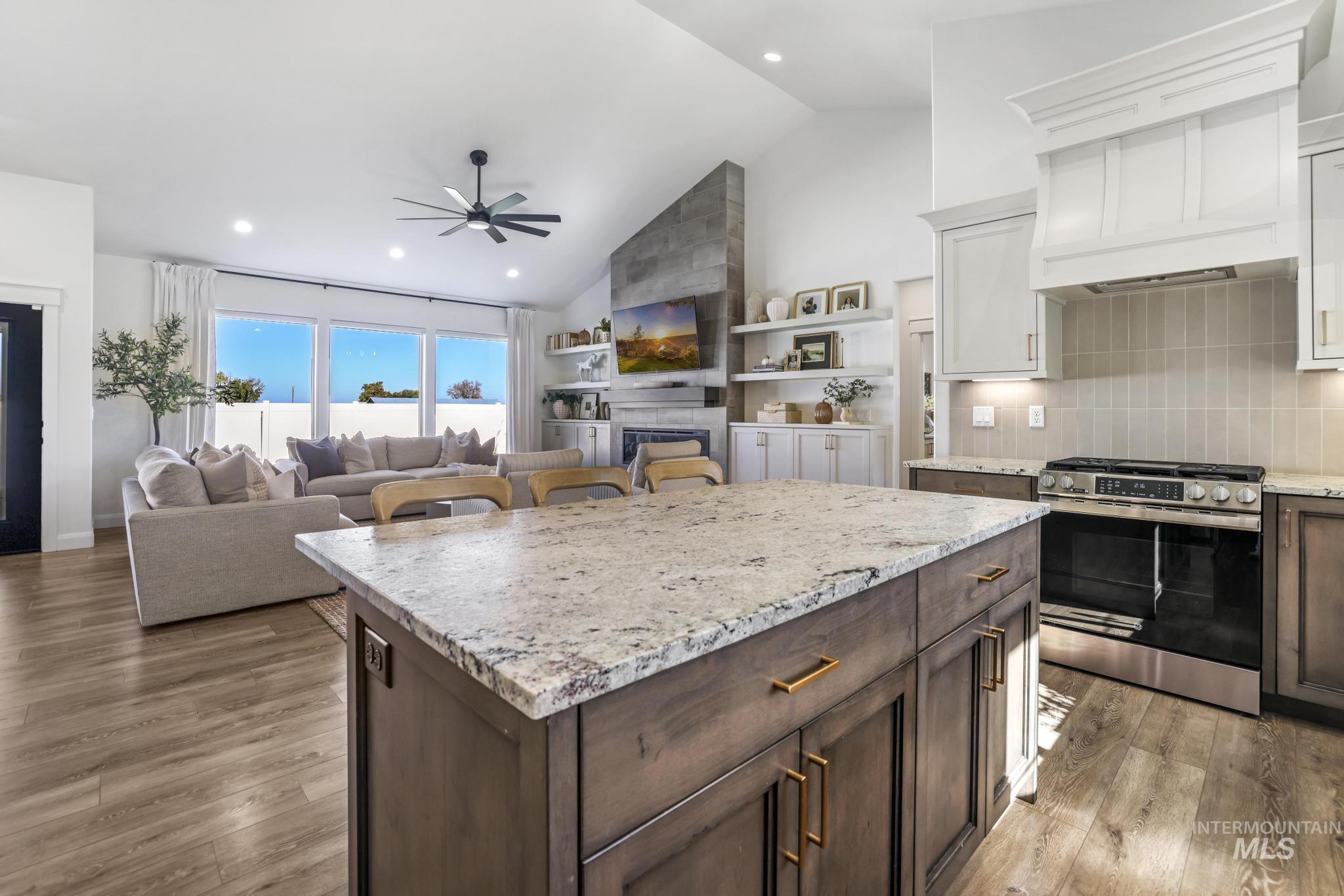 Kitchen featuring gas stove, decorative backsplash, dark brown cabinets, light stone countertops, and recessed lighting