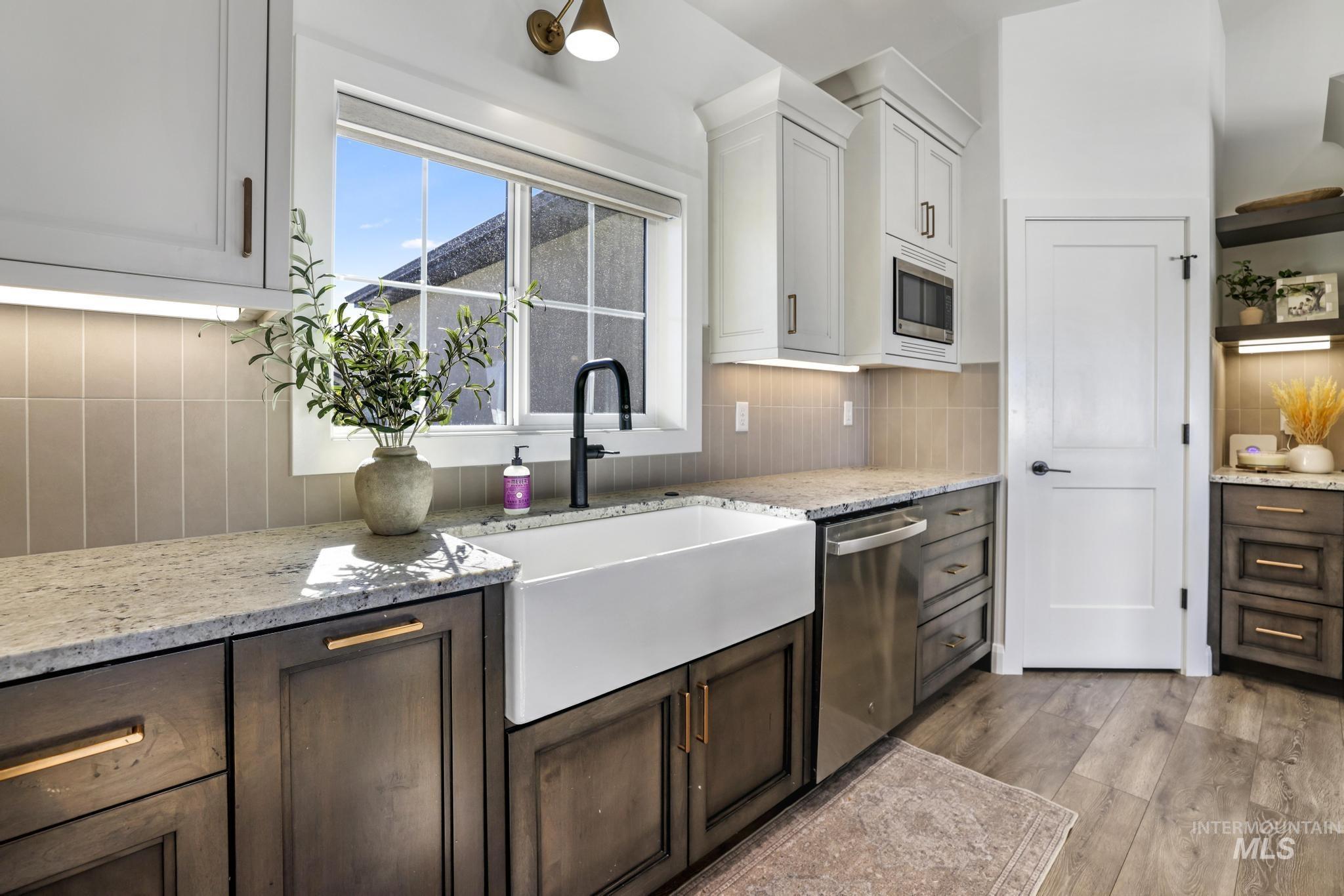 Kitchen featuring decorative backsplash, light stone counters, and white cabinetry