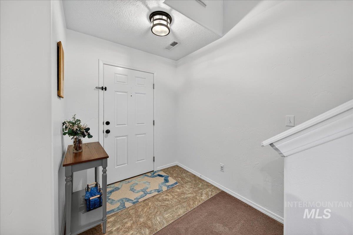 Entrance foyer featuring dark colored carpet and a textured ceiling