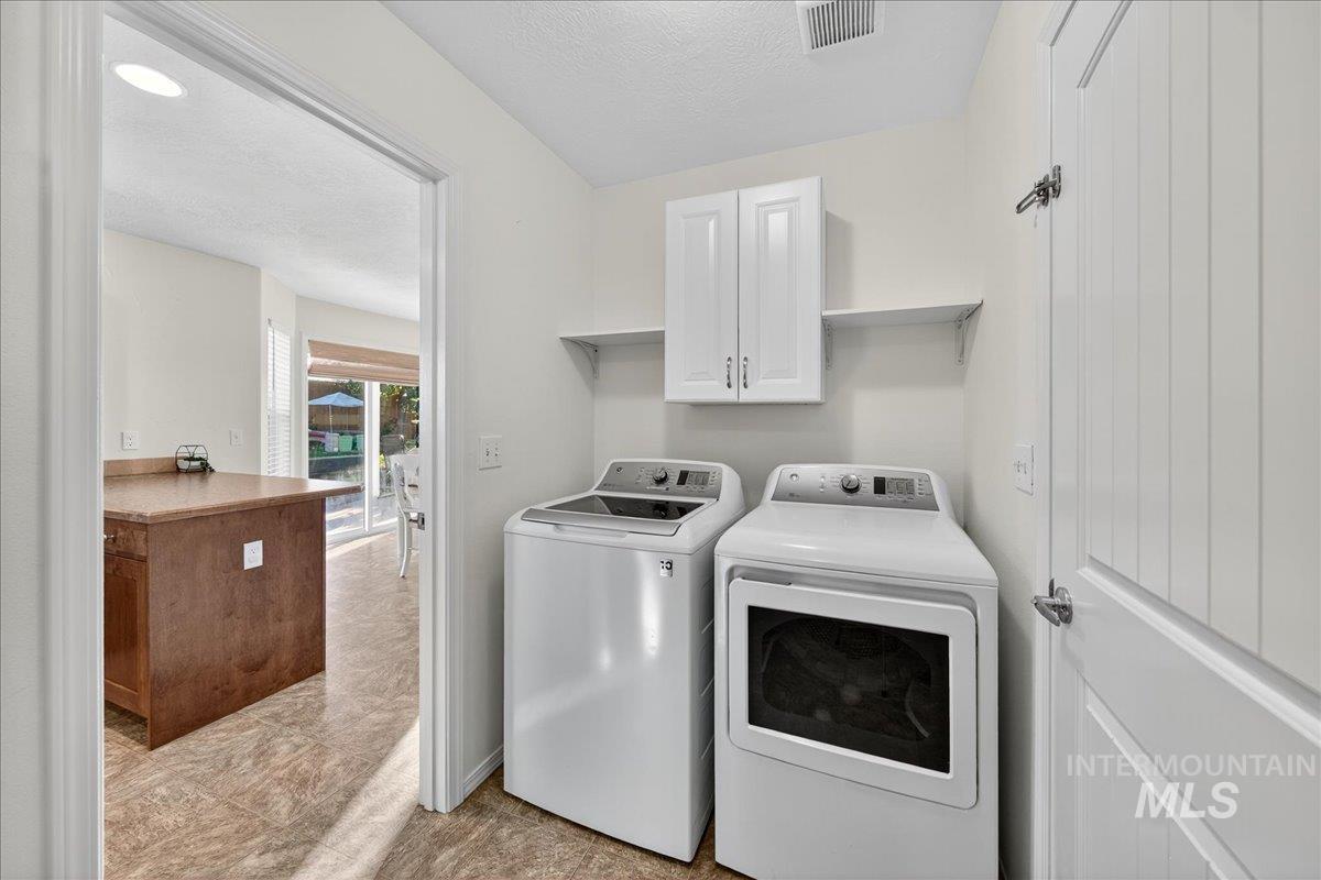 Laundry area with a textured ceiling, cabinet space, and washer and clothes dryer