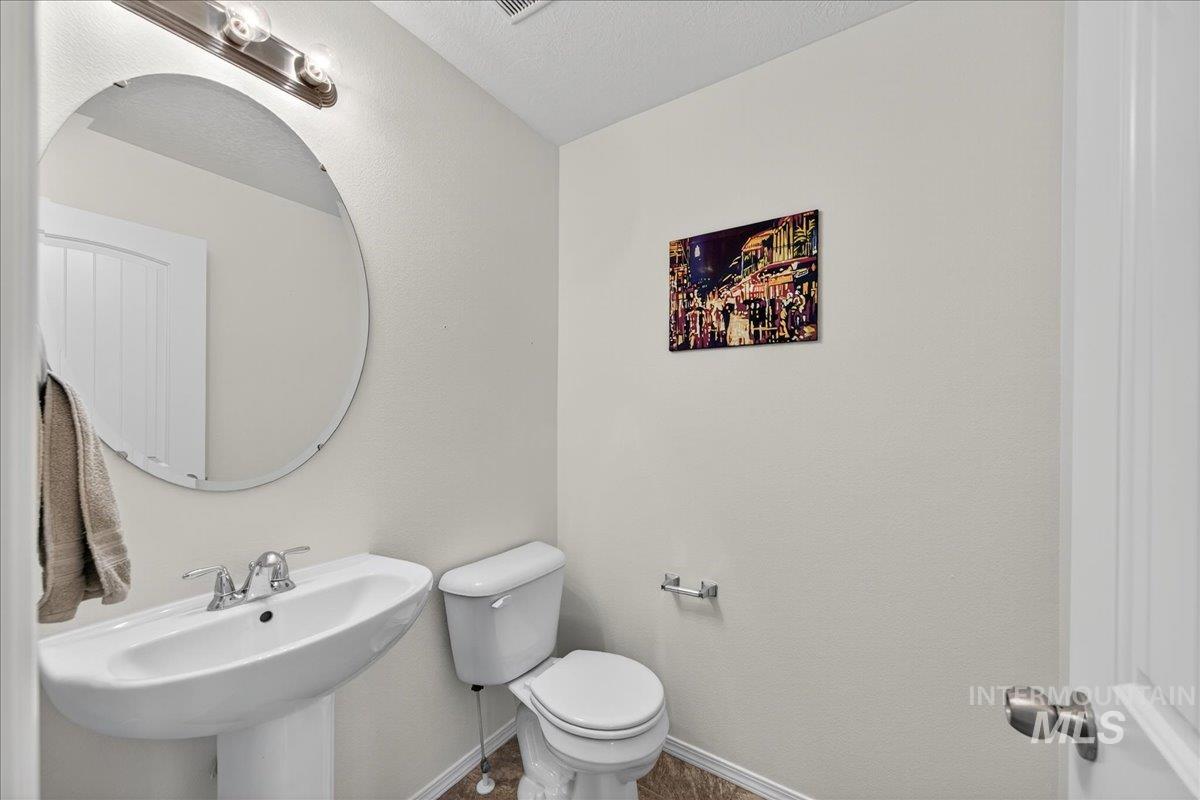 Half bath featuring toilet and baseboards