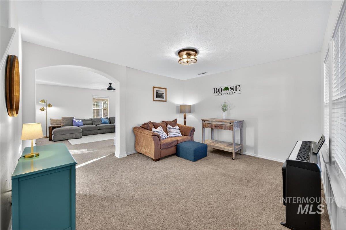 Sitting room featuring carpet floors, plenty of natural light, a textured ceiling, and arched walkways
