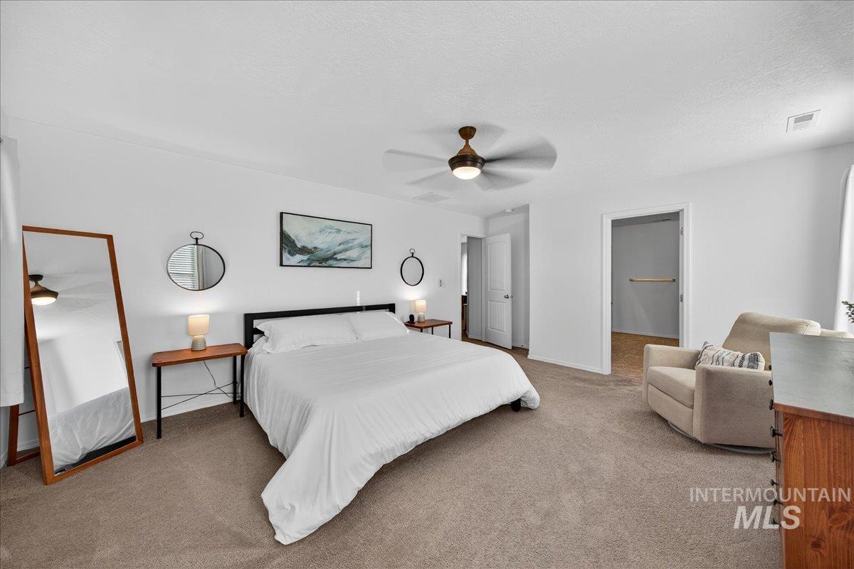 Carpeted bedroom with a ceiling fan and a textured ceiling
