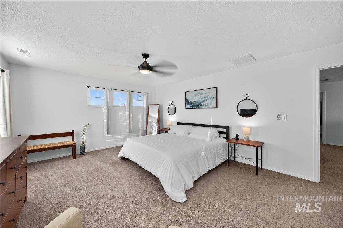 Bedroom featuring light colored carpet, a ceiling fan, and a textured ceiling