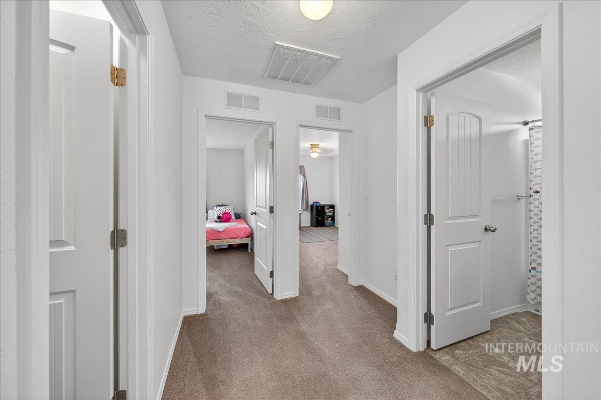 Corridor featuring carpet floors and a textured ceiling
