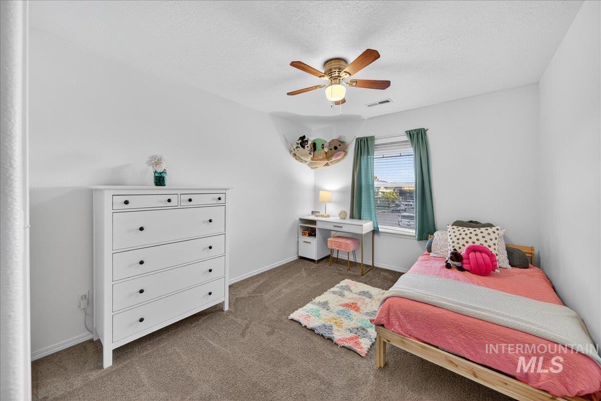 Carpeted bedroom featuring a ceiling fan and a textured ceiling