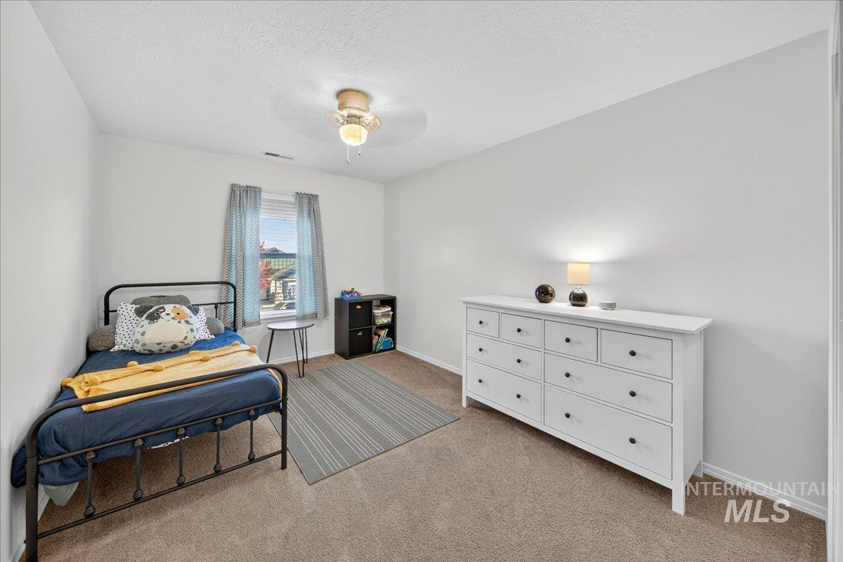 Bedroom featuring light colored carpet, a textured ceiling, and ceiling fan