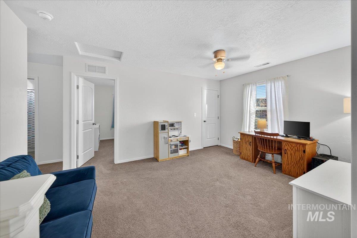 Office area featuring light carpet, a textured ceiling, ceiling fan, and attic access