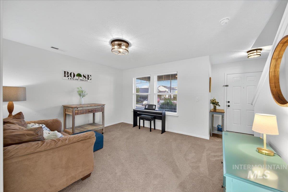 Living area featuring light carpet and a textured ceiling