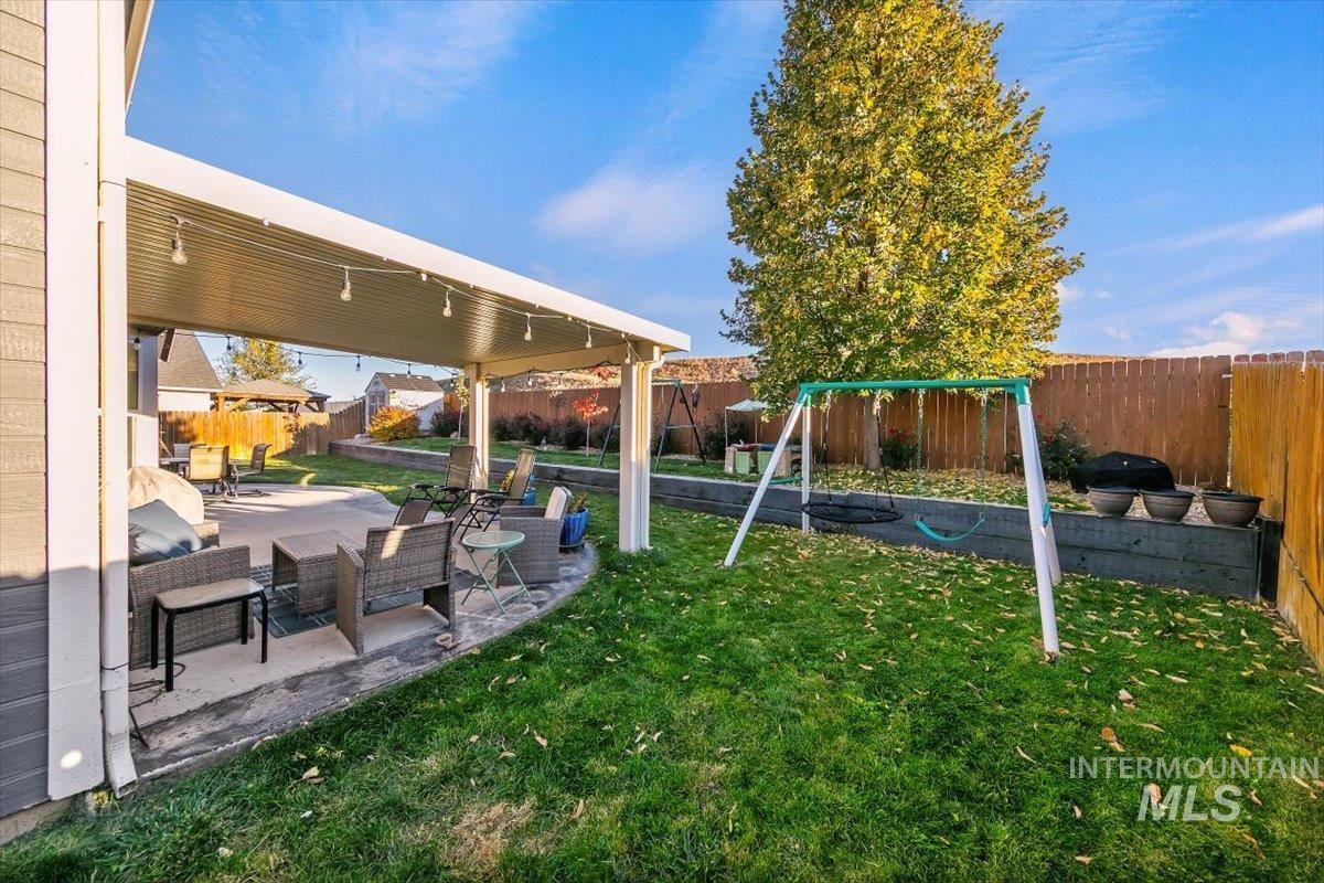 Fenced backyard featuring a playground and a patio