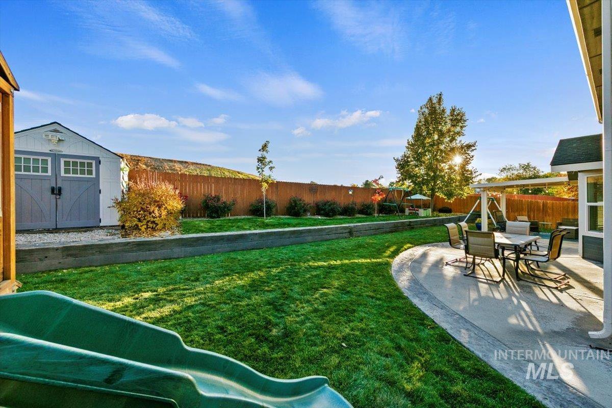 Fenced backyard featuring a storage shed and a patio area