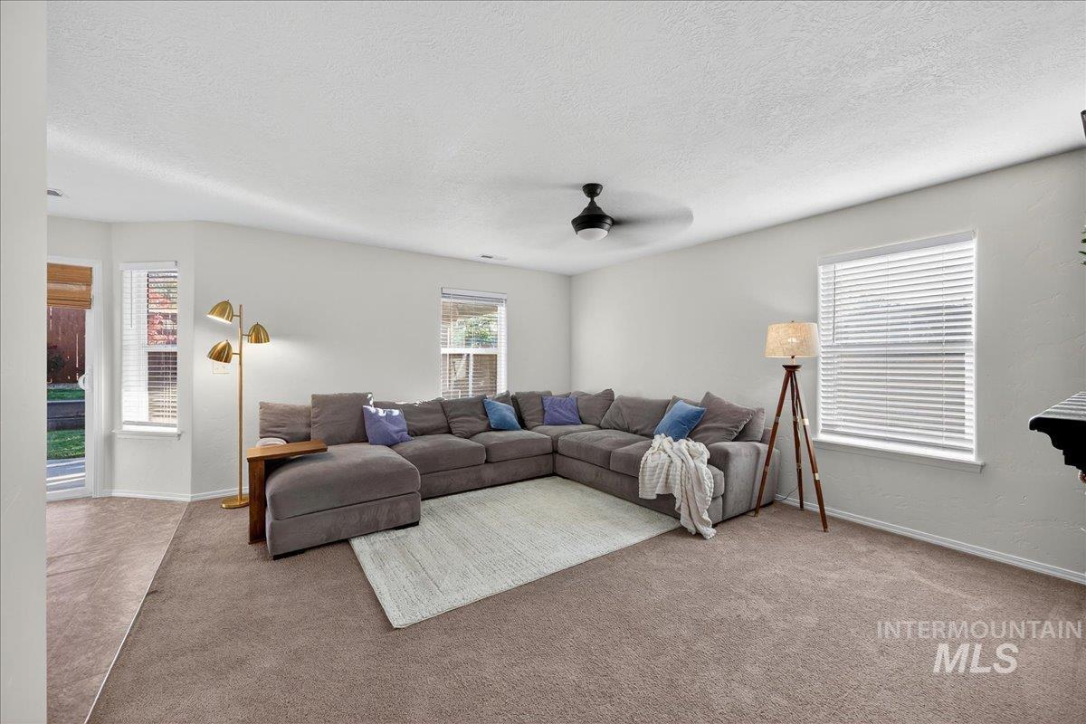Carpeted living room with a textured ceiling and ceiling fan