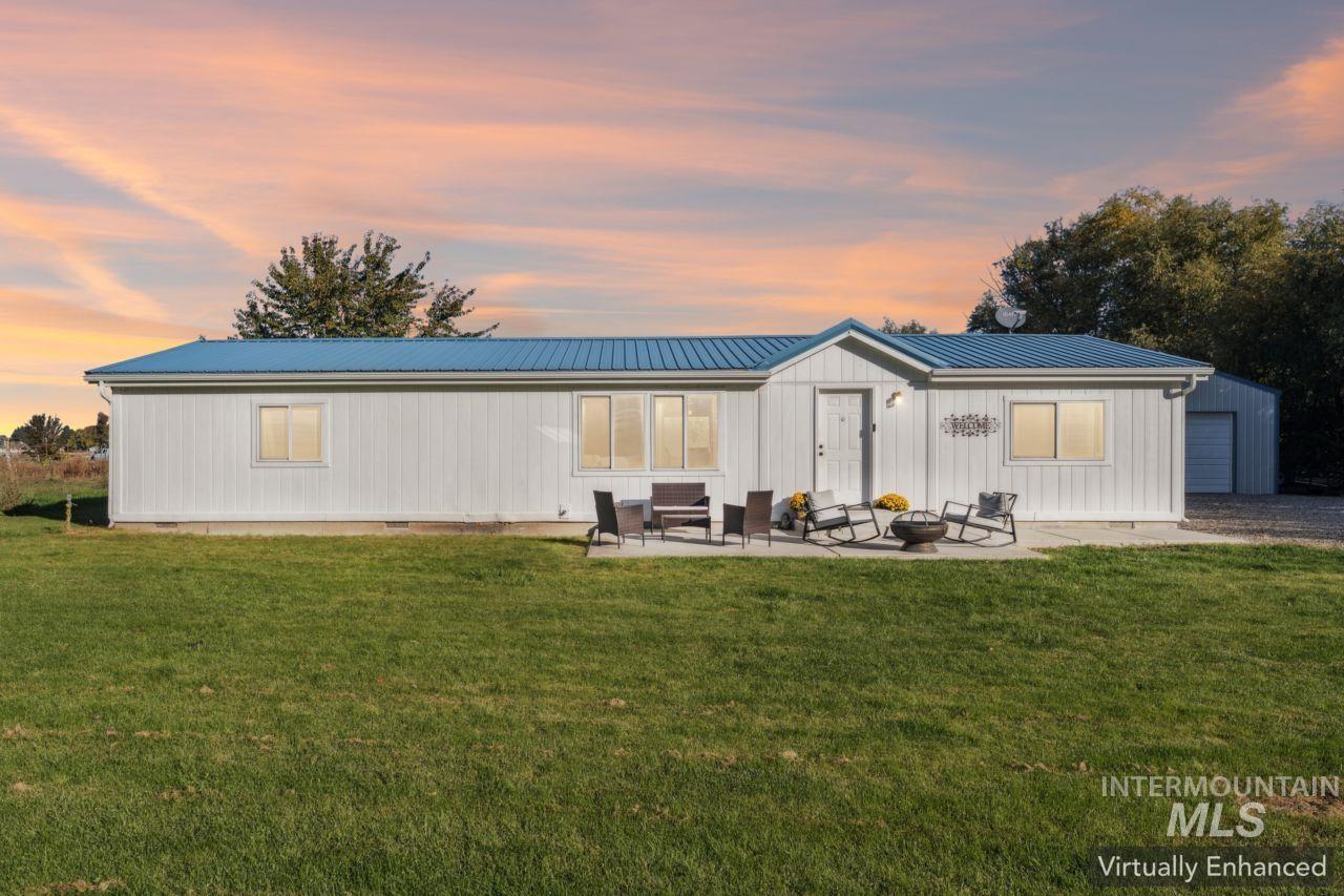 Back of house with crawl space, a metal roof, a lawn, and a patio