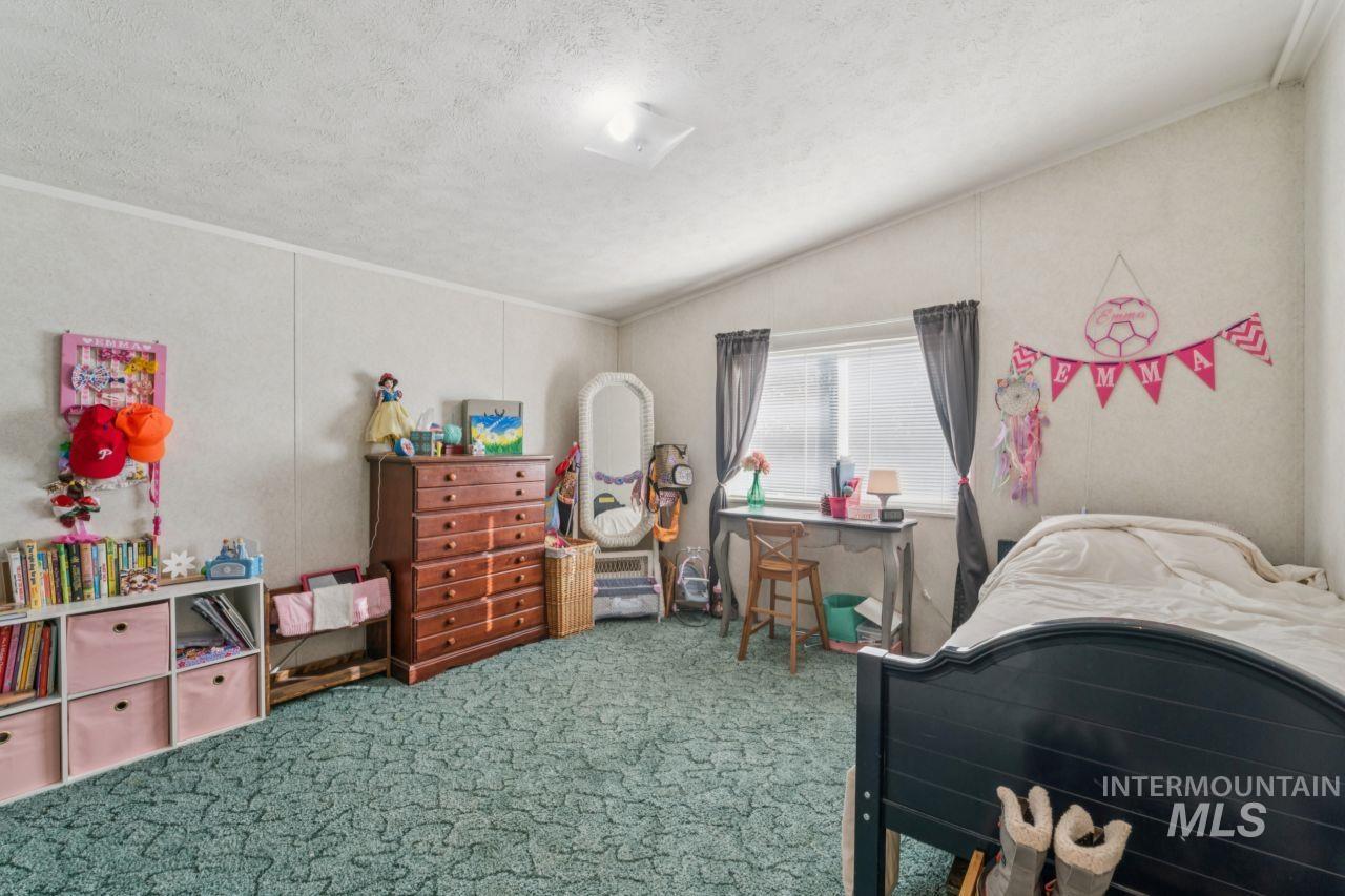 Carpeted bedroom featuring a textured ceiling, lofted ceiling, and ornamental molding