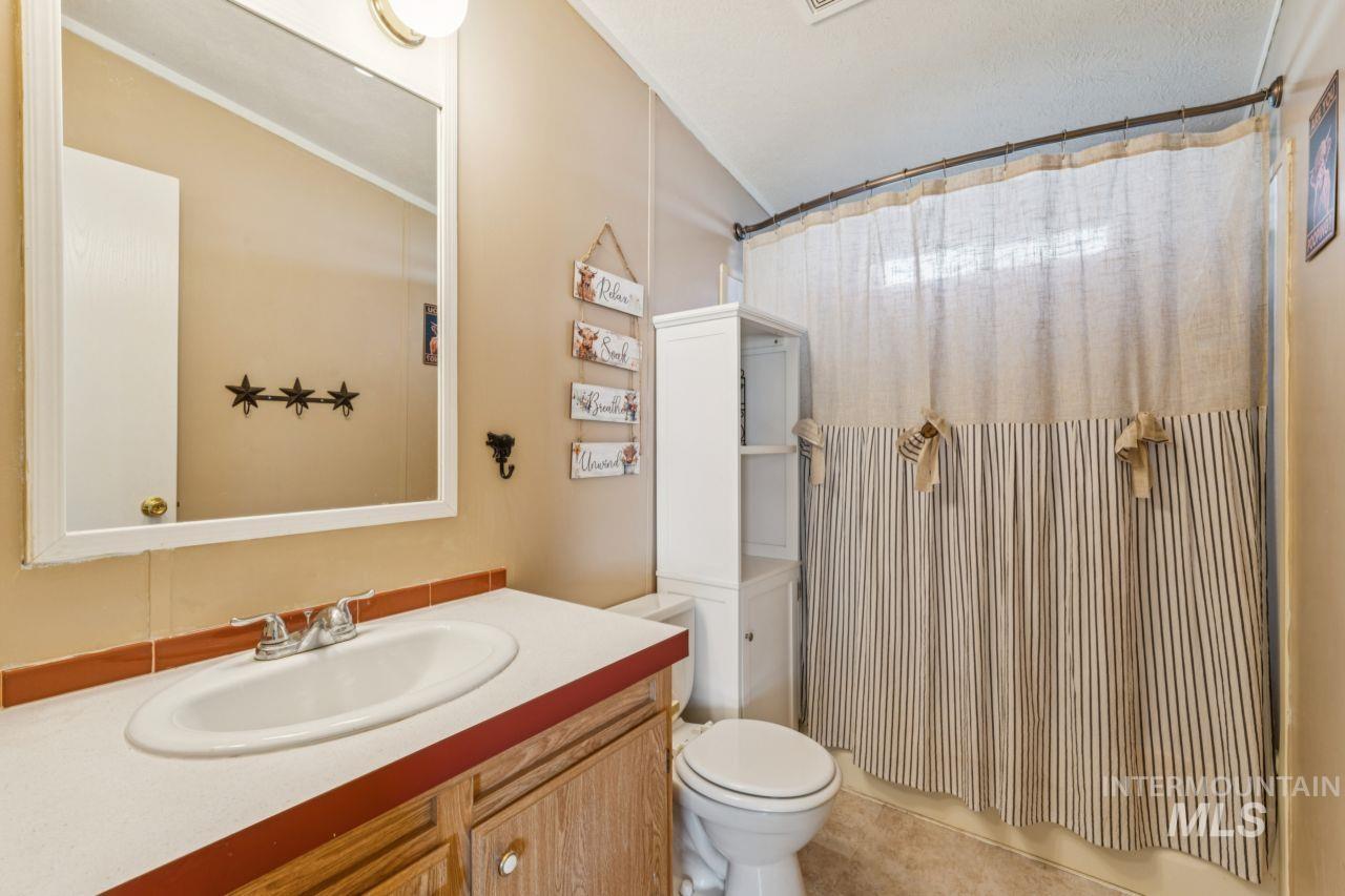 Full bathroom featuring vanity, lofted ceiling, and light tile patterned floors