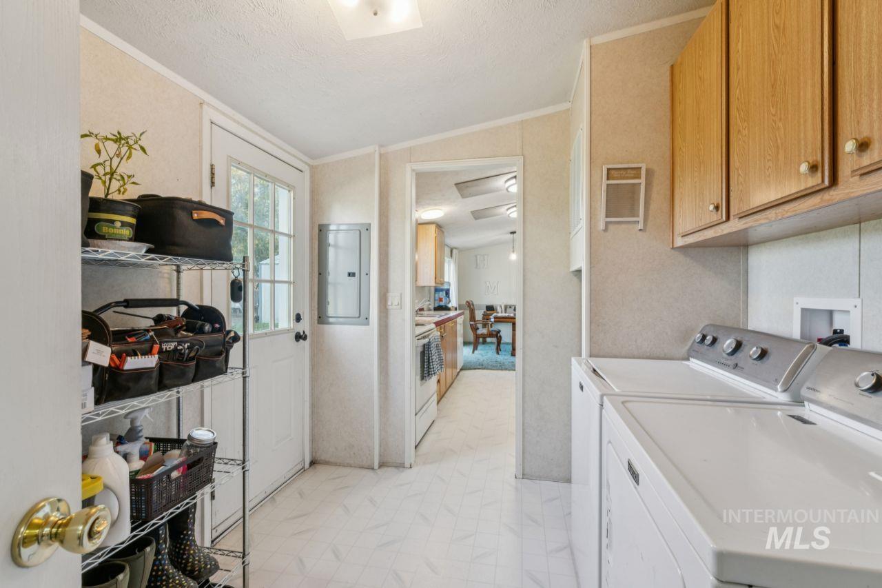 Laundry room featuring lofted ceiling, electric panel, washing machine and dryer, crown molding, and cabinet space