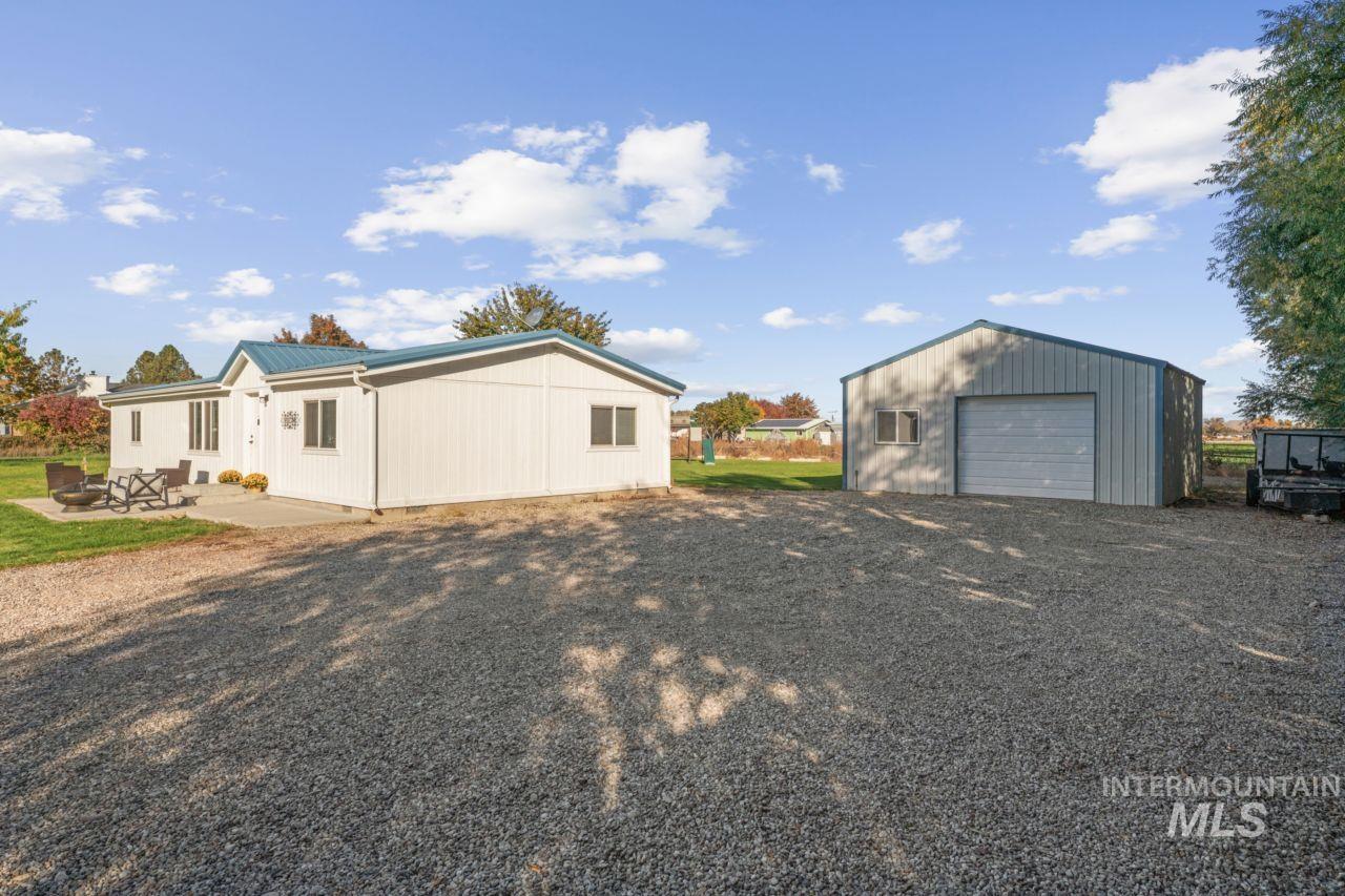 Back of property featuring a garage, an outbuilding, a metal roof, and a patio