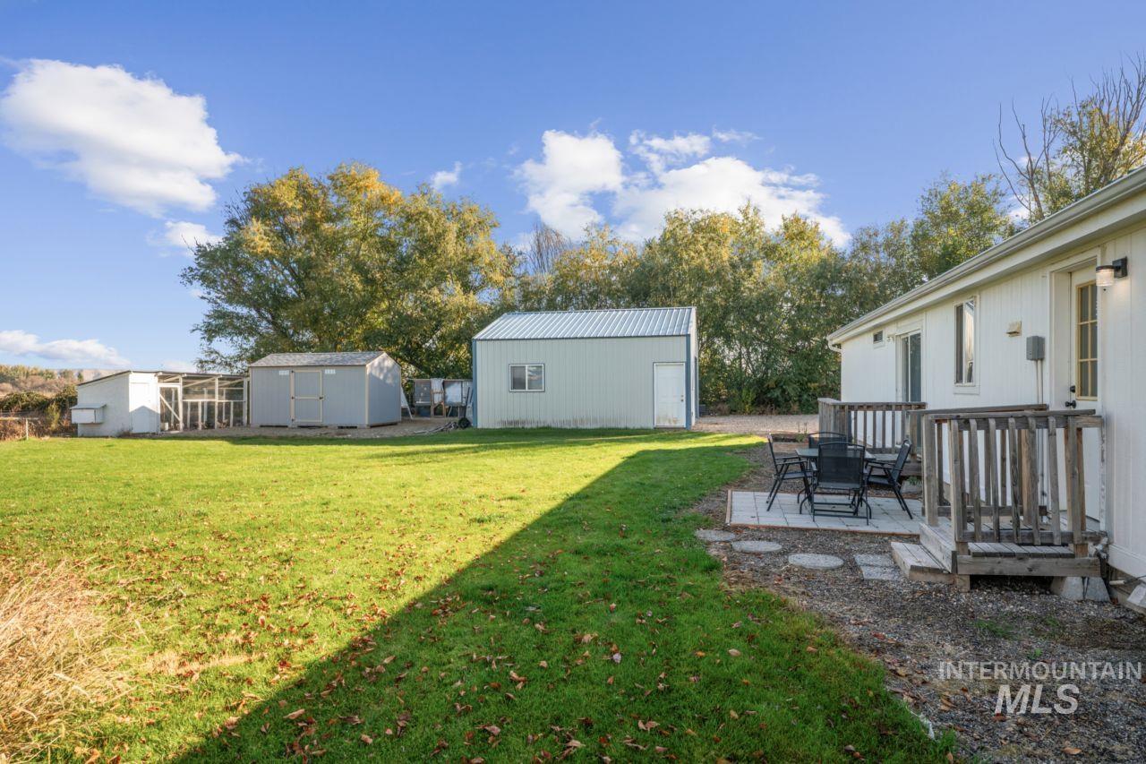View of grassy yard featuring an outbuilding and a wooden deck