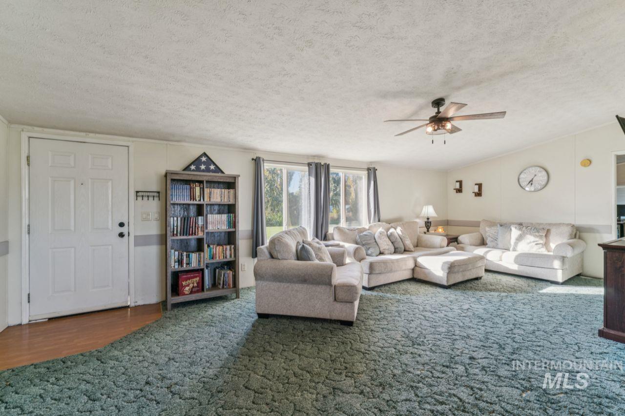 Living area featuring a textured ceiling, wood finished floors, ceiling fan, and carpet flooring