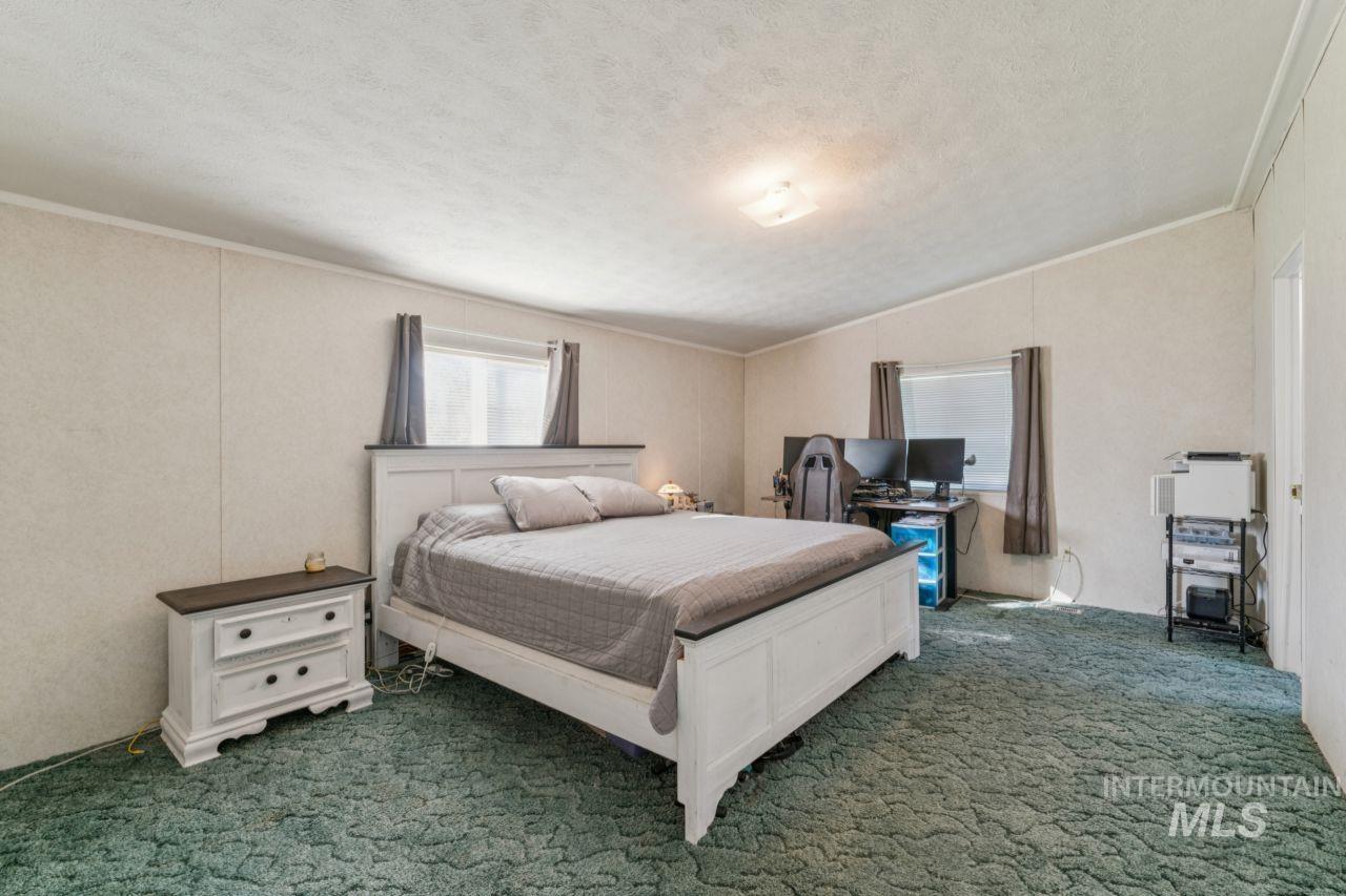 Carpeted bedroom with a textured ceiling and ornamental molding