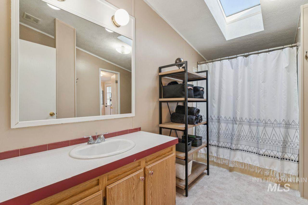 Full bathroom with curtained shower, vanity, a skylight, and crown molding