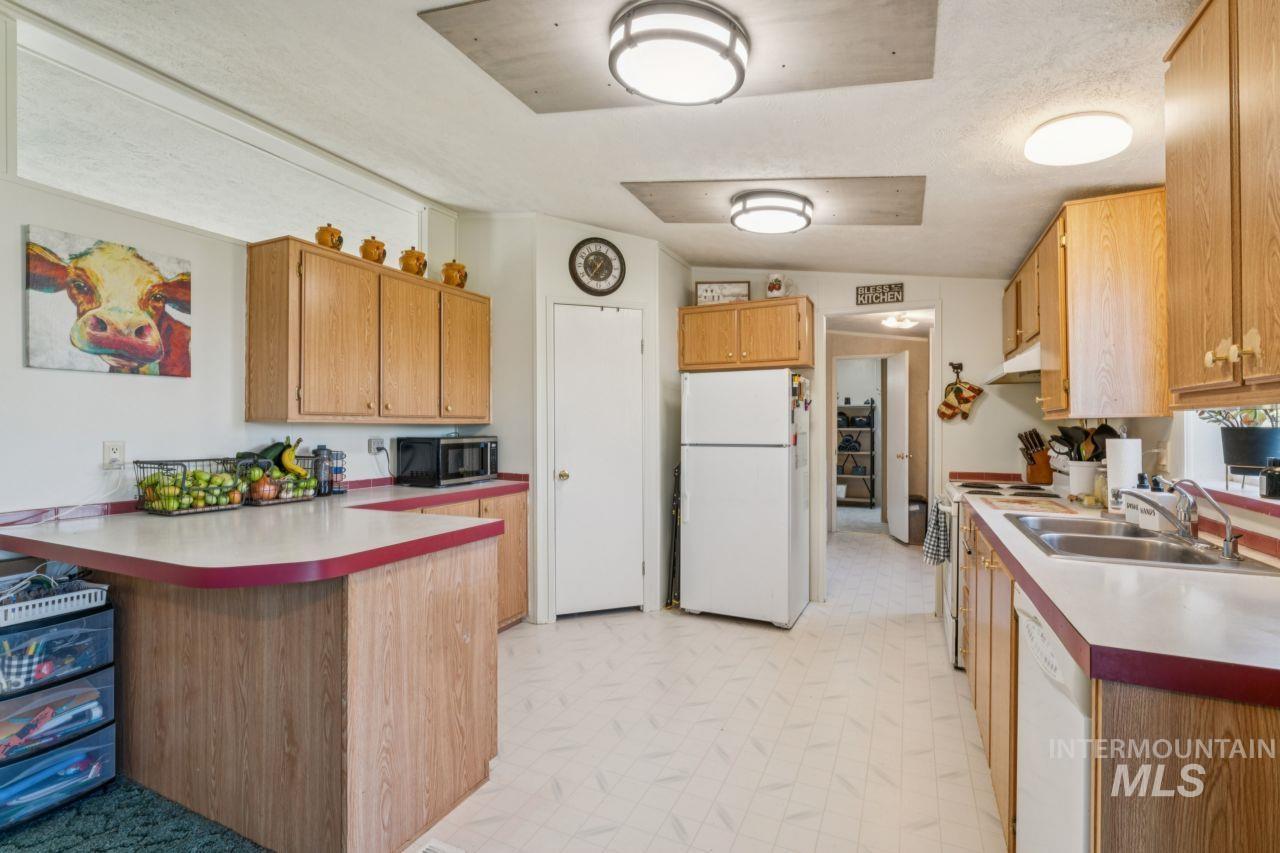 Kitchen with a peninsula, white appliances, light floors, light countertops, and a textured ceiling