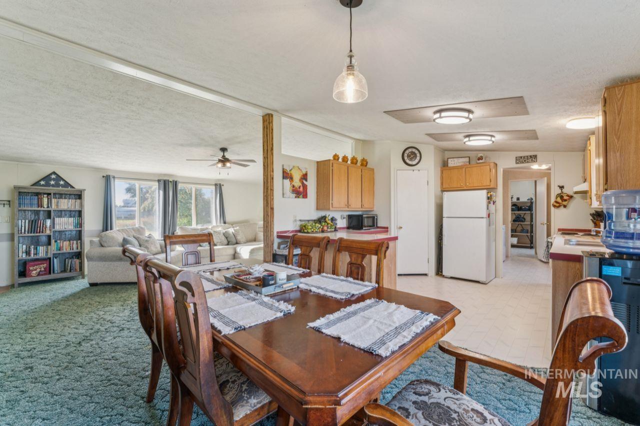 Dining area with a textured ceiling, ceiling fan, and light colored carpet
