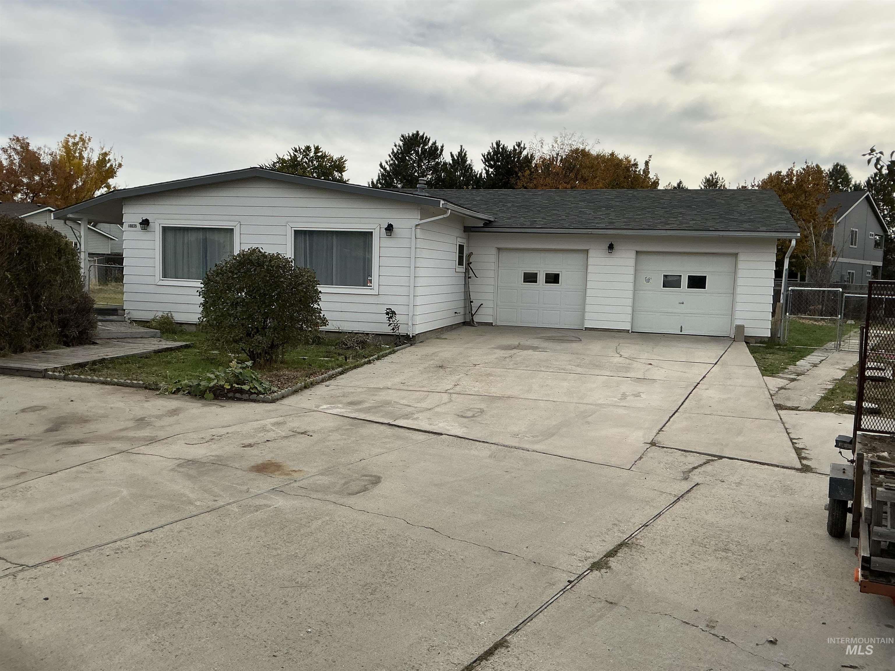 Single story home with concrete driveway, a garage, and a gate