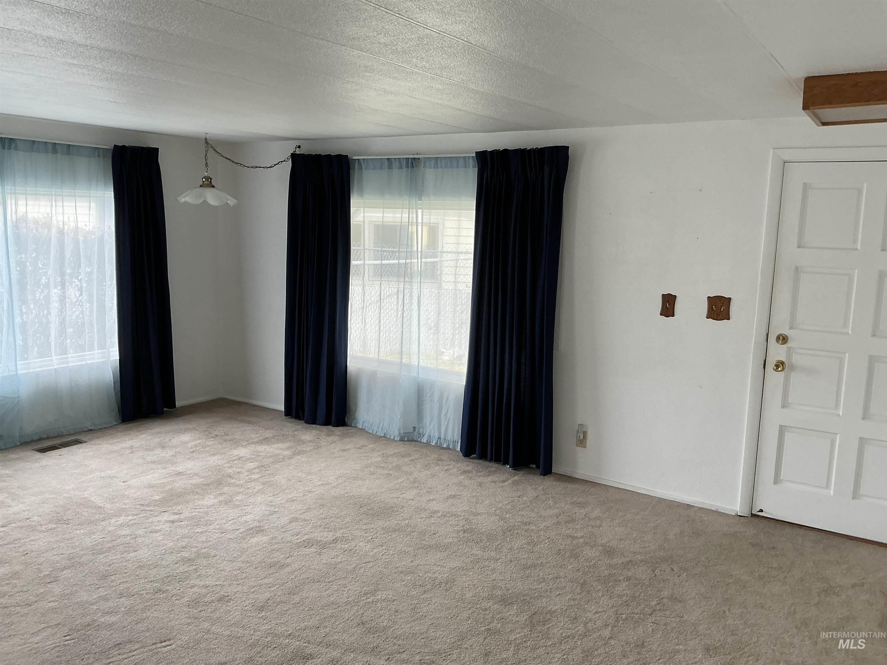 Unfurnished room with a textured ceiling and light colored carpet
