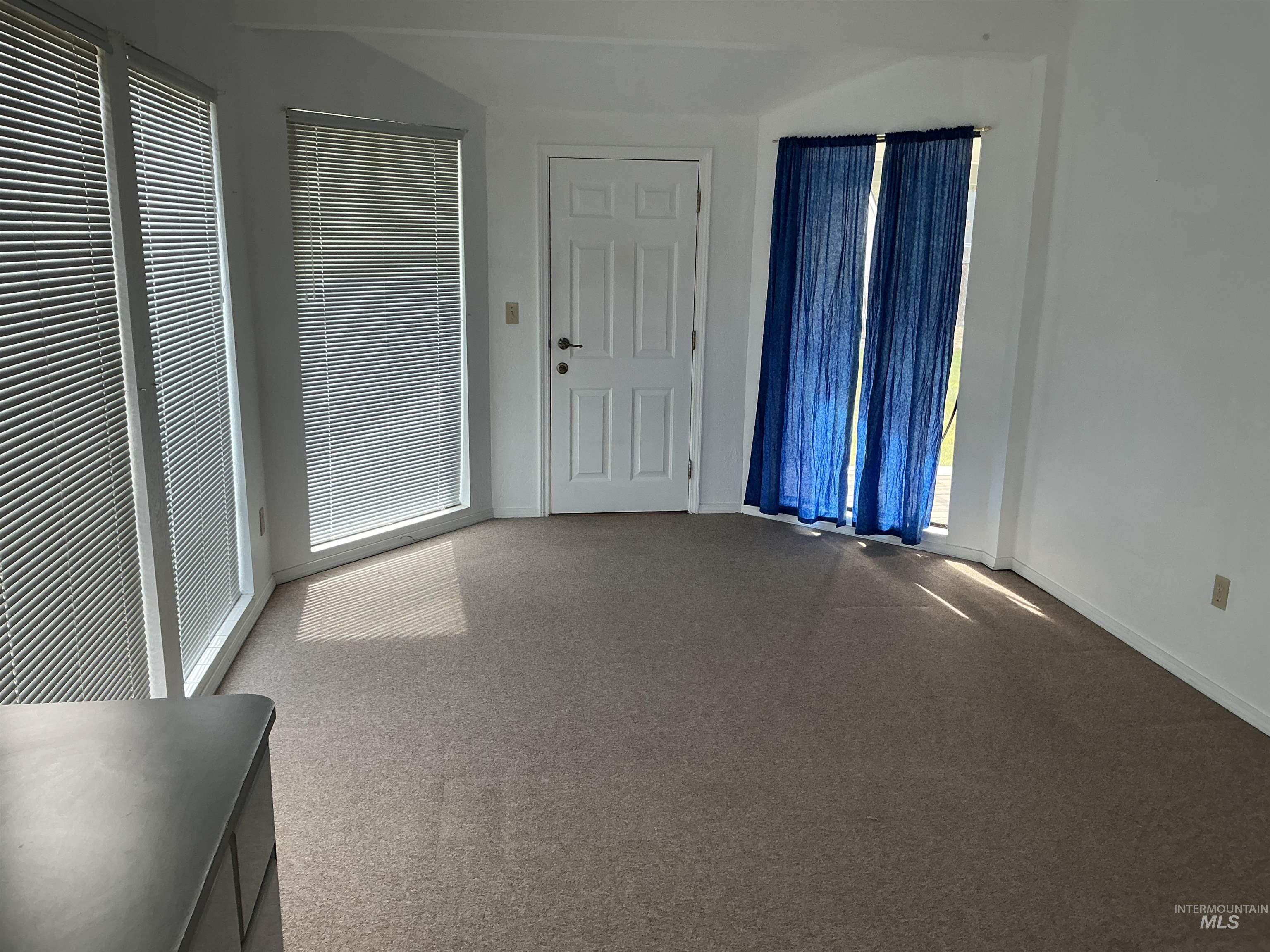 Unfurnished living room featuring carpet floors and baseboards