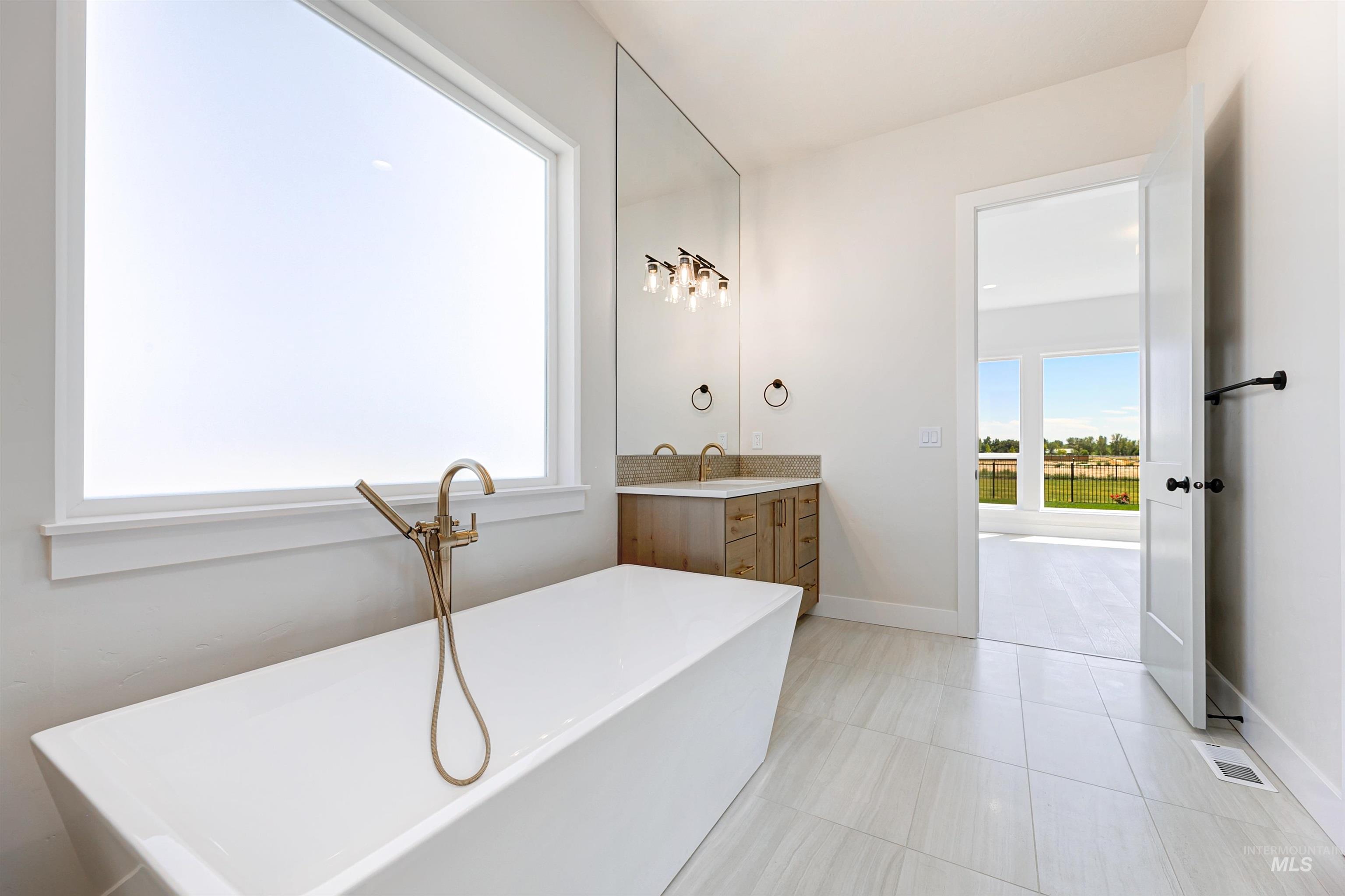 Bathroom with vanity, light tile patterned floors, and a freestanding bath