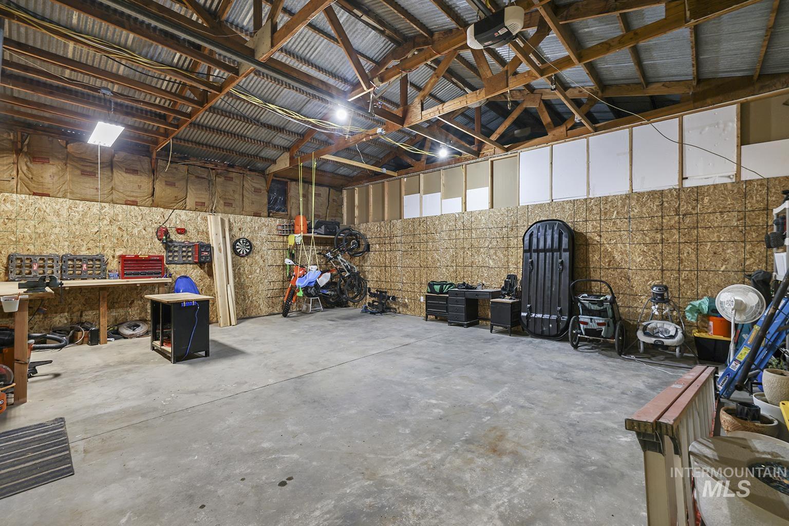 Garage featuring metal wall, a workshop area, and a garage door opener
