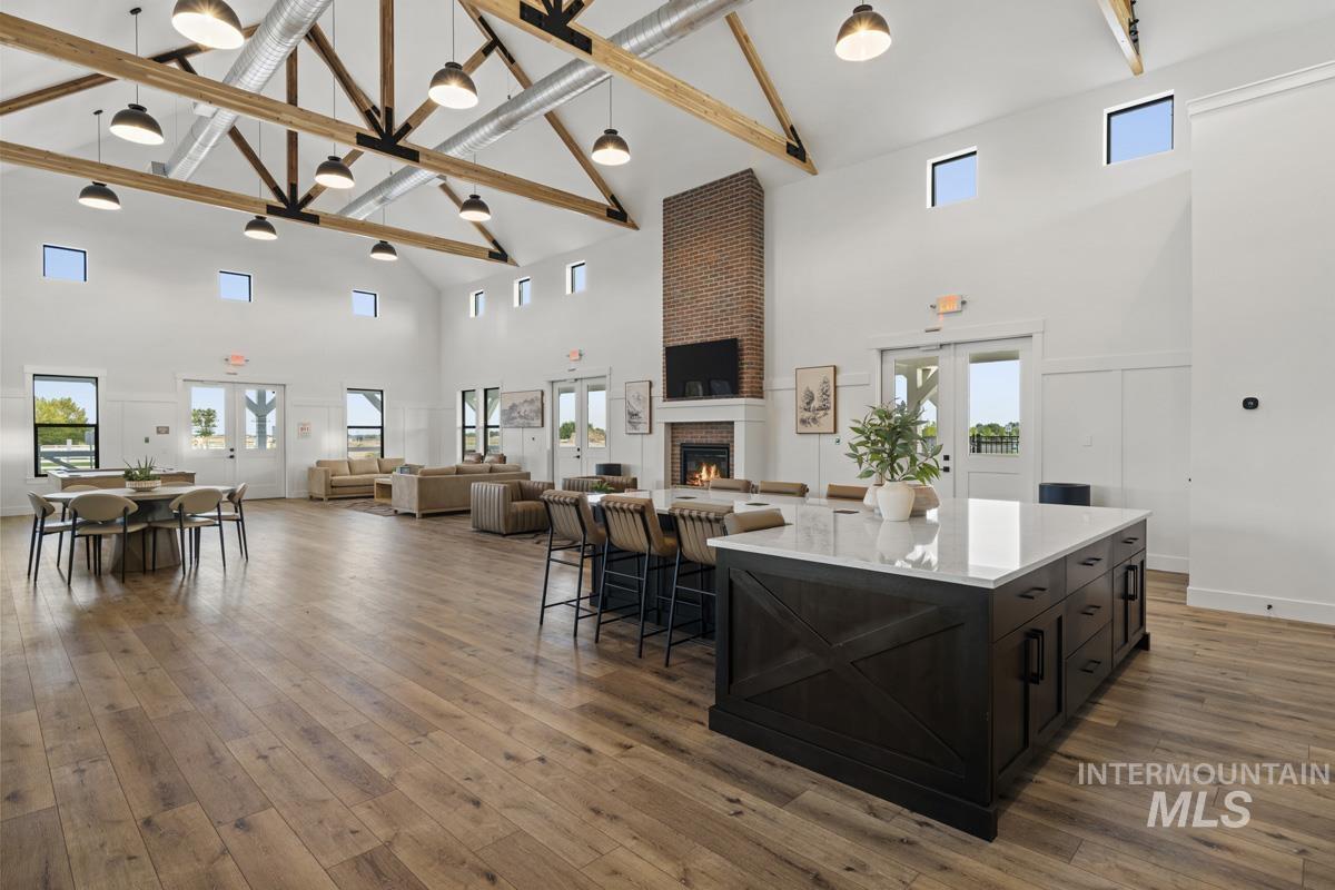 Kitchen with high vaulted ceiling, a brick fireplace, dark cabinets, open floor plan, and decorative light fixtures