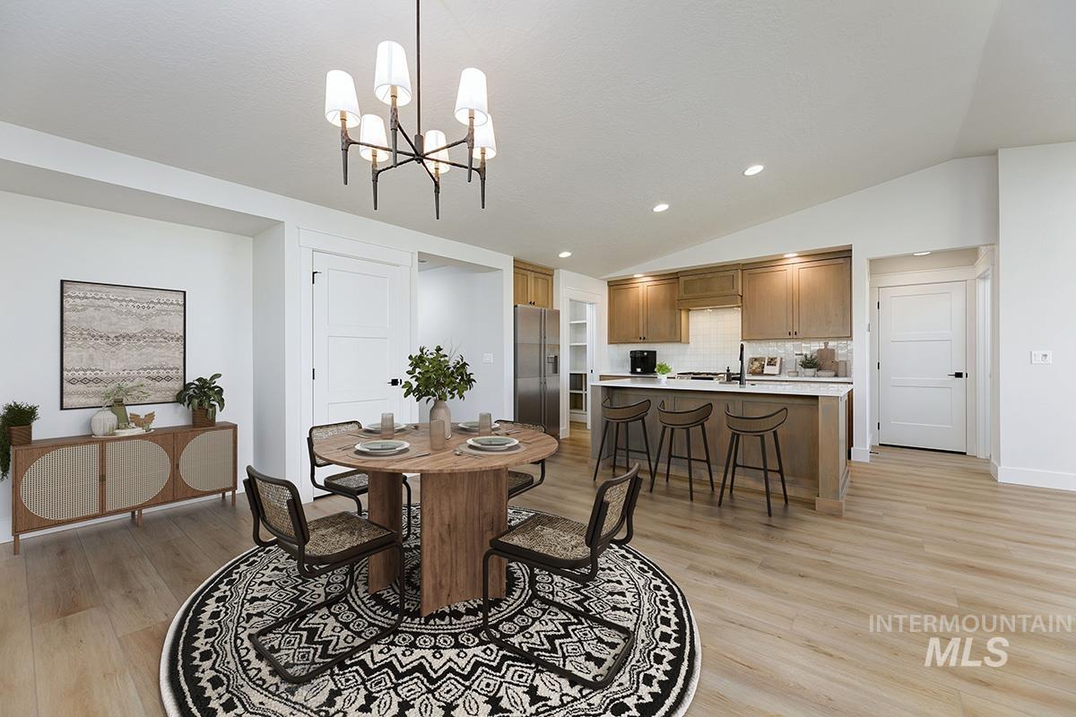 Dining area with recessed lighting, vaulted ceiling, light wood-style flooring, and a chandelier