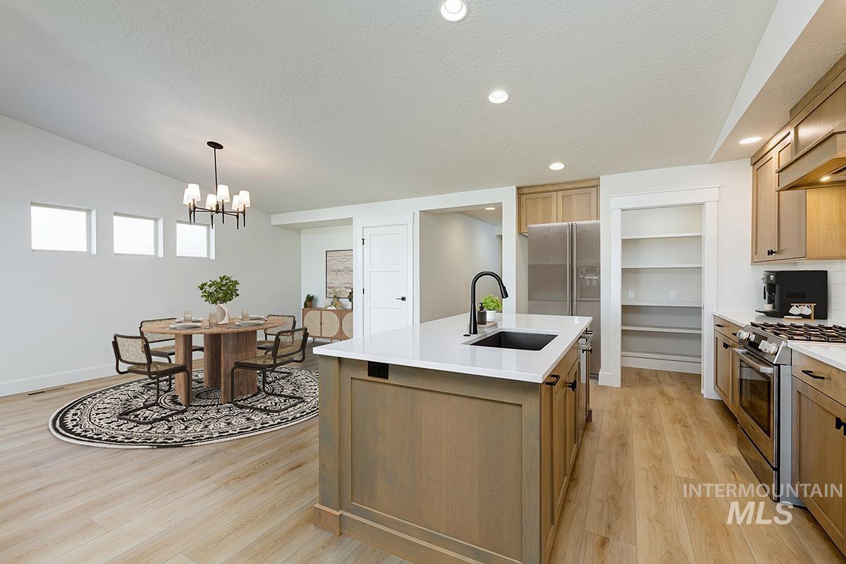 Kitchen with gas range, recessed lighting, light wood-type flooring, an island with sink, and pendant lighting