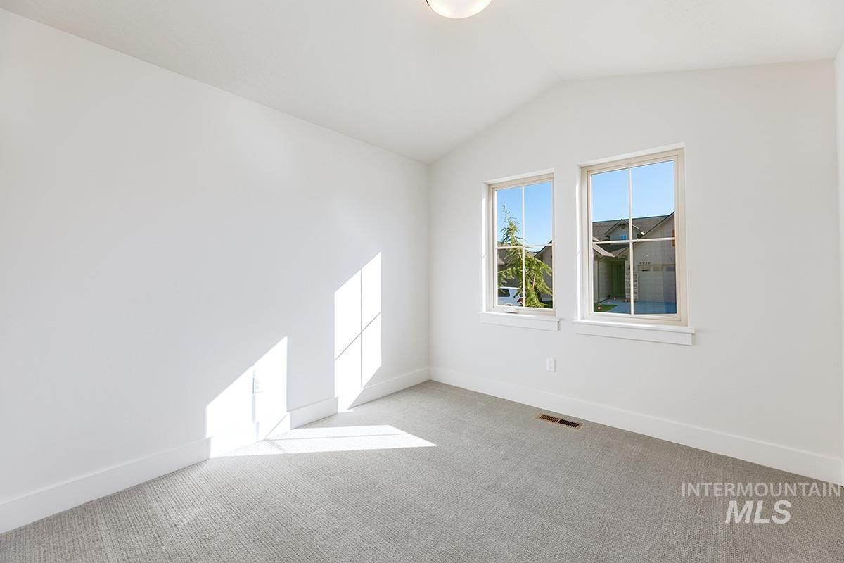 Carpeted spare room featuring baseboards and lofted ceiling