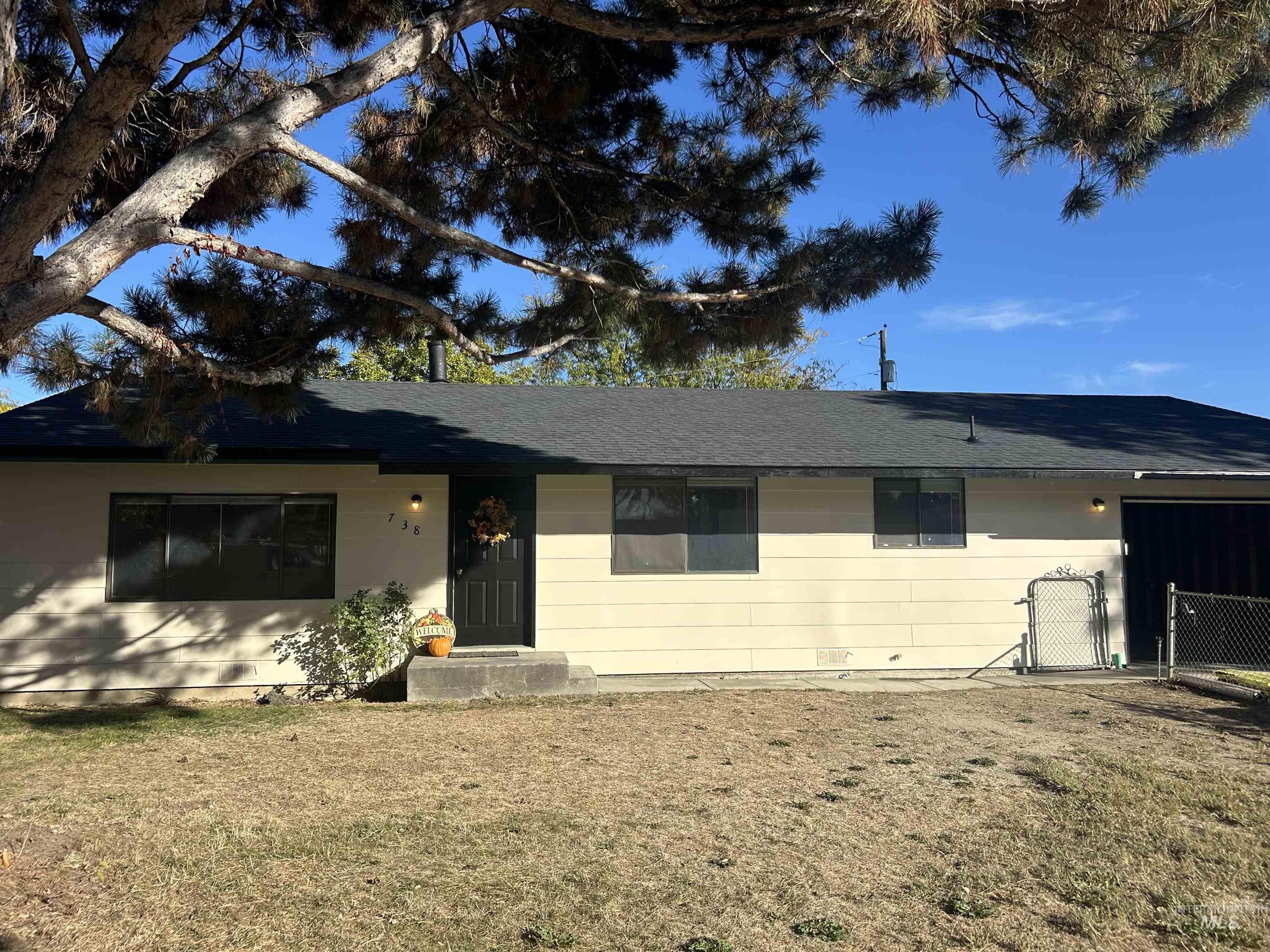 Single story home with roof with shingles, a gate, and a front lawn