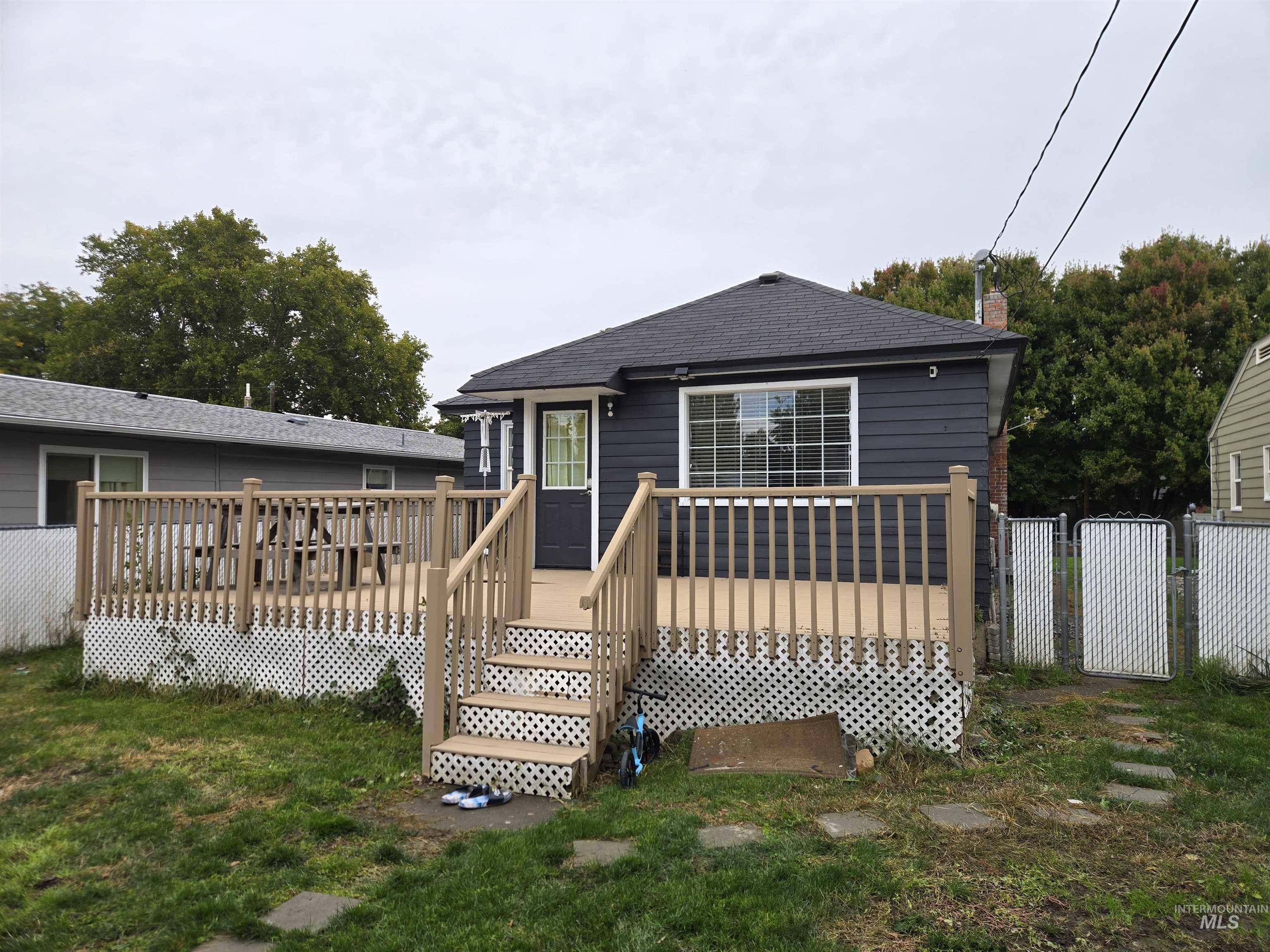 View of front of home with a gate, a wooden deck, and roof with shingles
