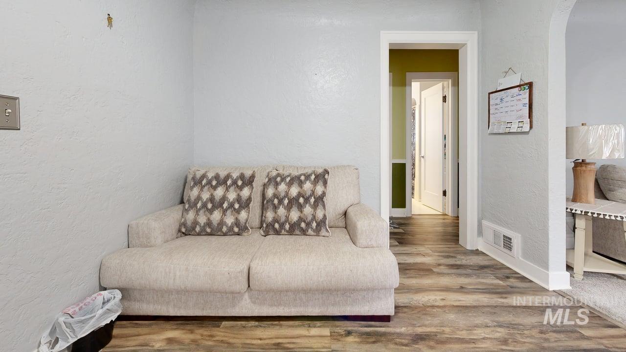 Living area featuring a textured wall, wood finished floors, and arched walkways