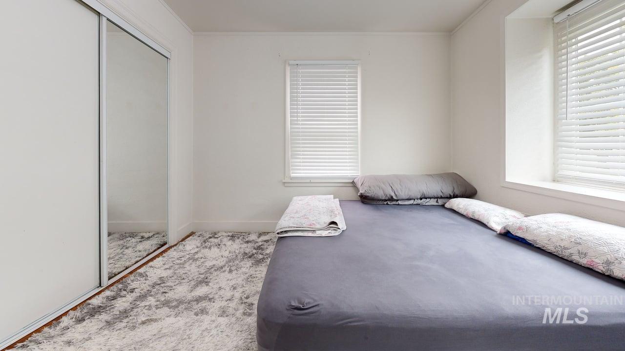 Bedroom with a closet, crown molding, and carpet flooring